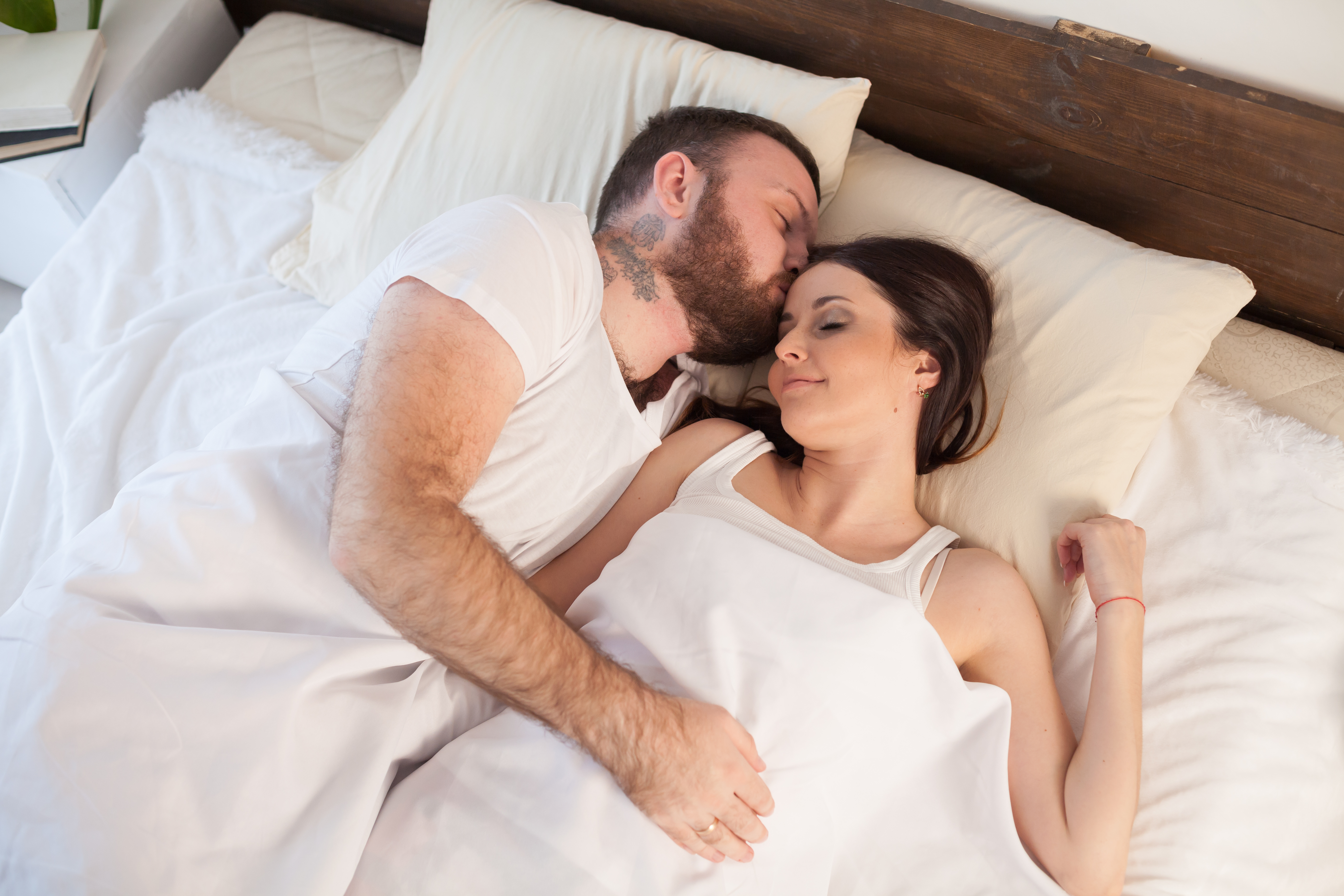 Un hombre besa a su esposa en la cama | Fuente: Getty Images