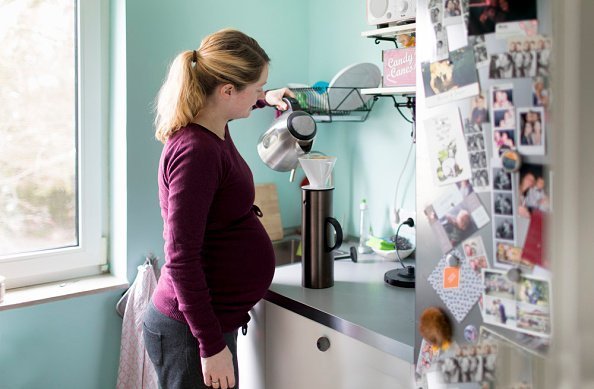 Una mujer embarazada en la foto preparando café en su cocina. | Foto: Getty Images