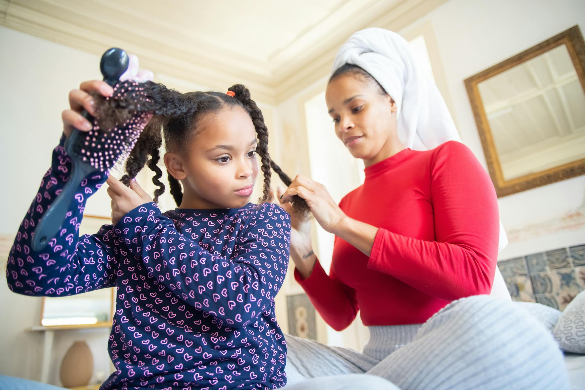 Una madre trenzando el pelo de su hija | Fuente: Pexels