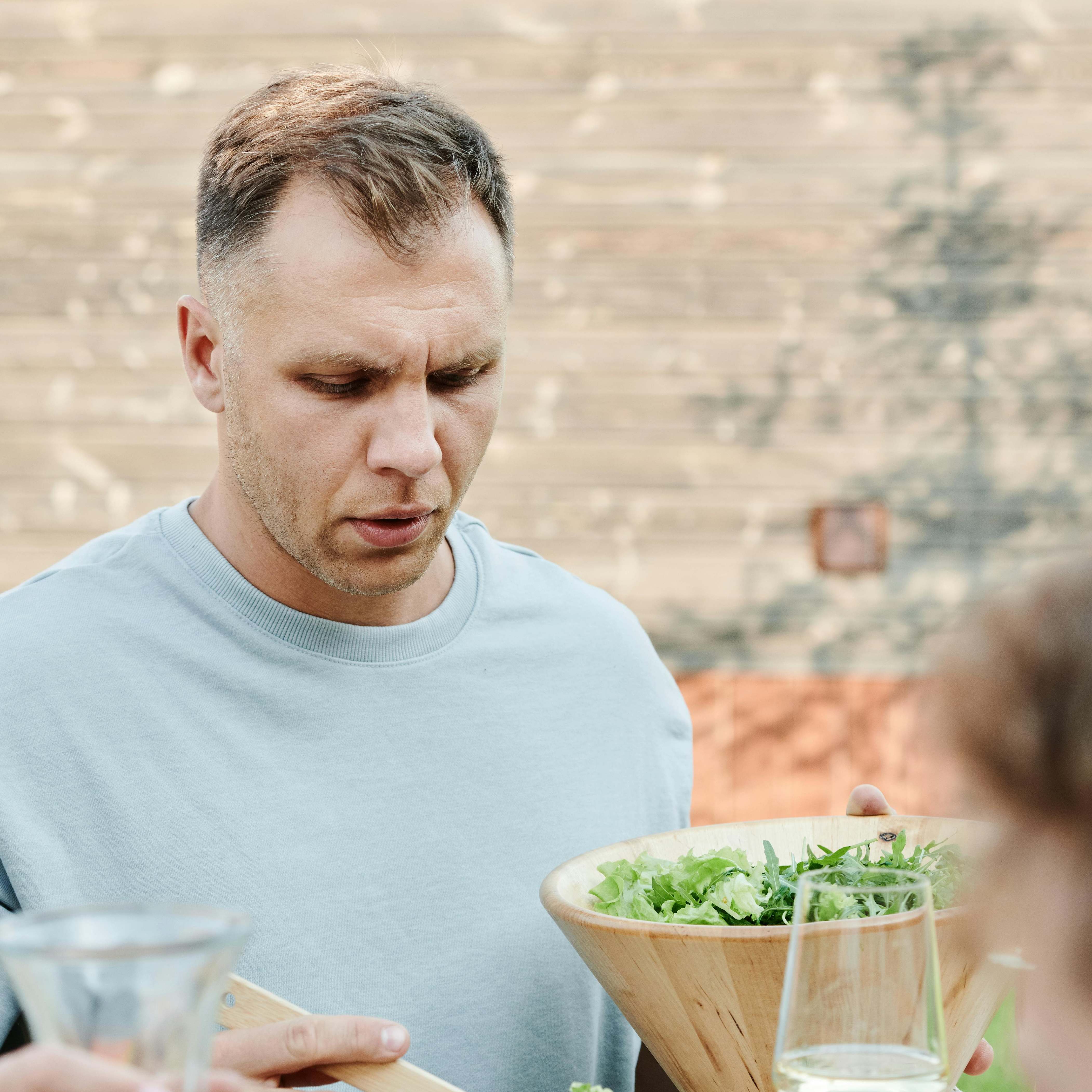 Un hombre sirviéndose de una ensaladera | Fuente: Pexels