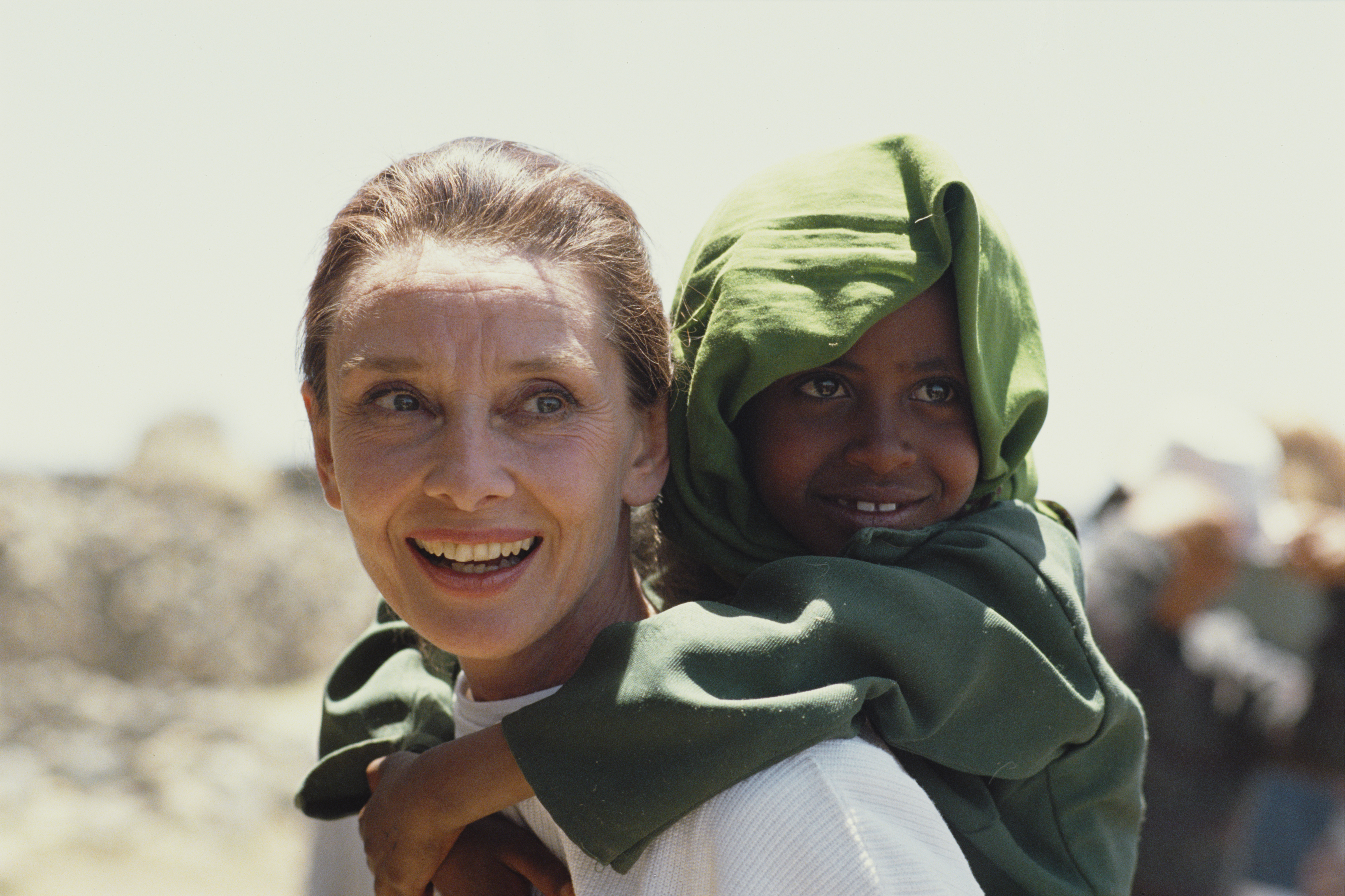 Audrey Hepburn con una niña etíope a la espalda durante su primera misión sobre el terreno para UNICEF en Etiopía, en marzo de 1988. | Fuente: Getty Images
