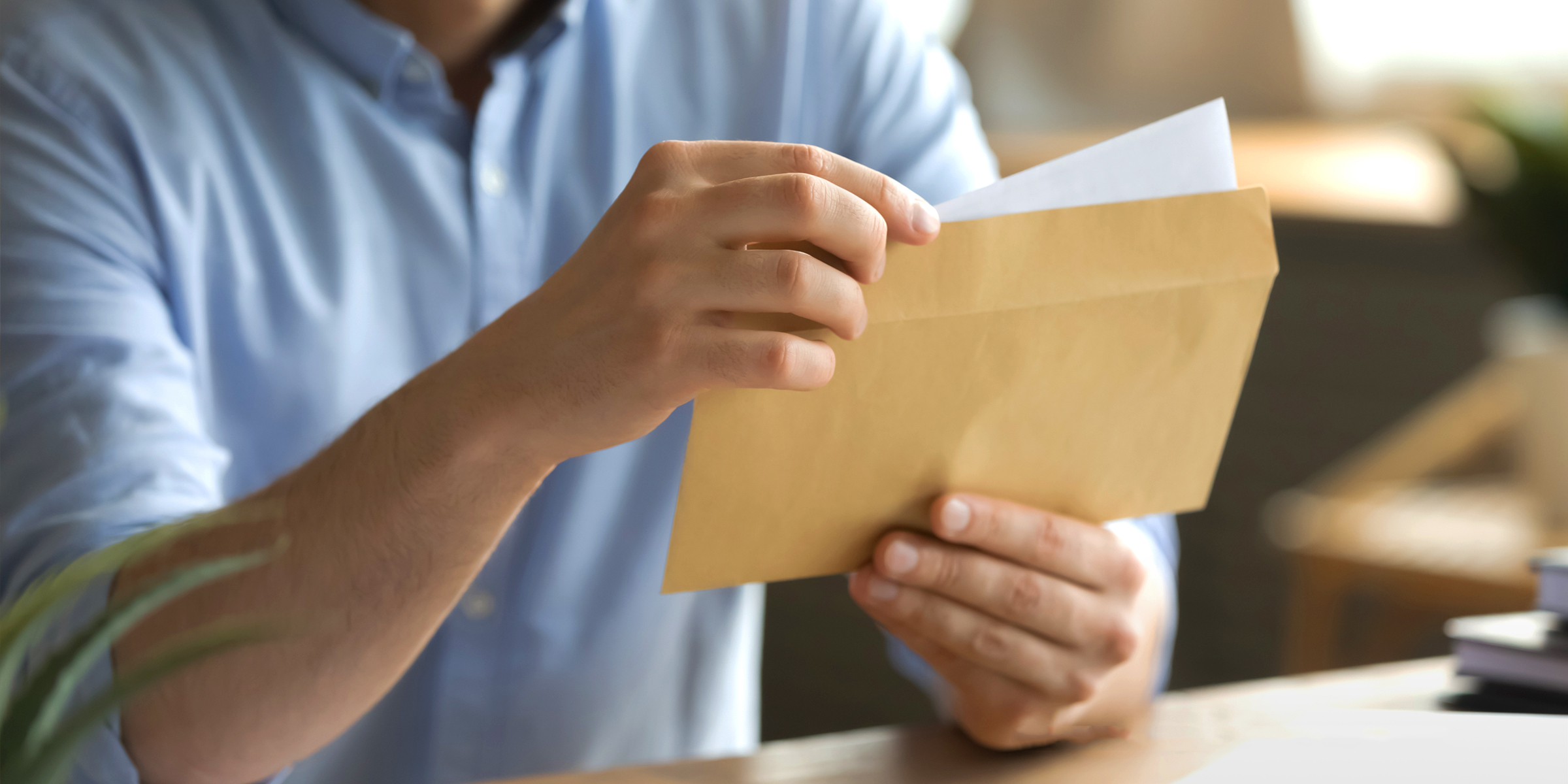 Un hombre abriendo un sobre y sacando una carta | Fuente: Shutterstock