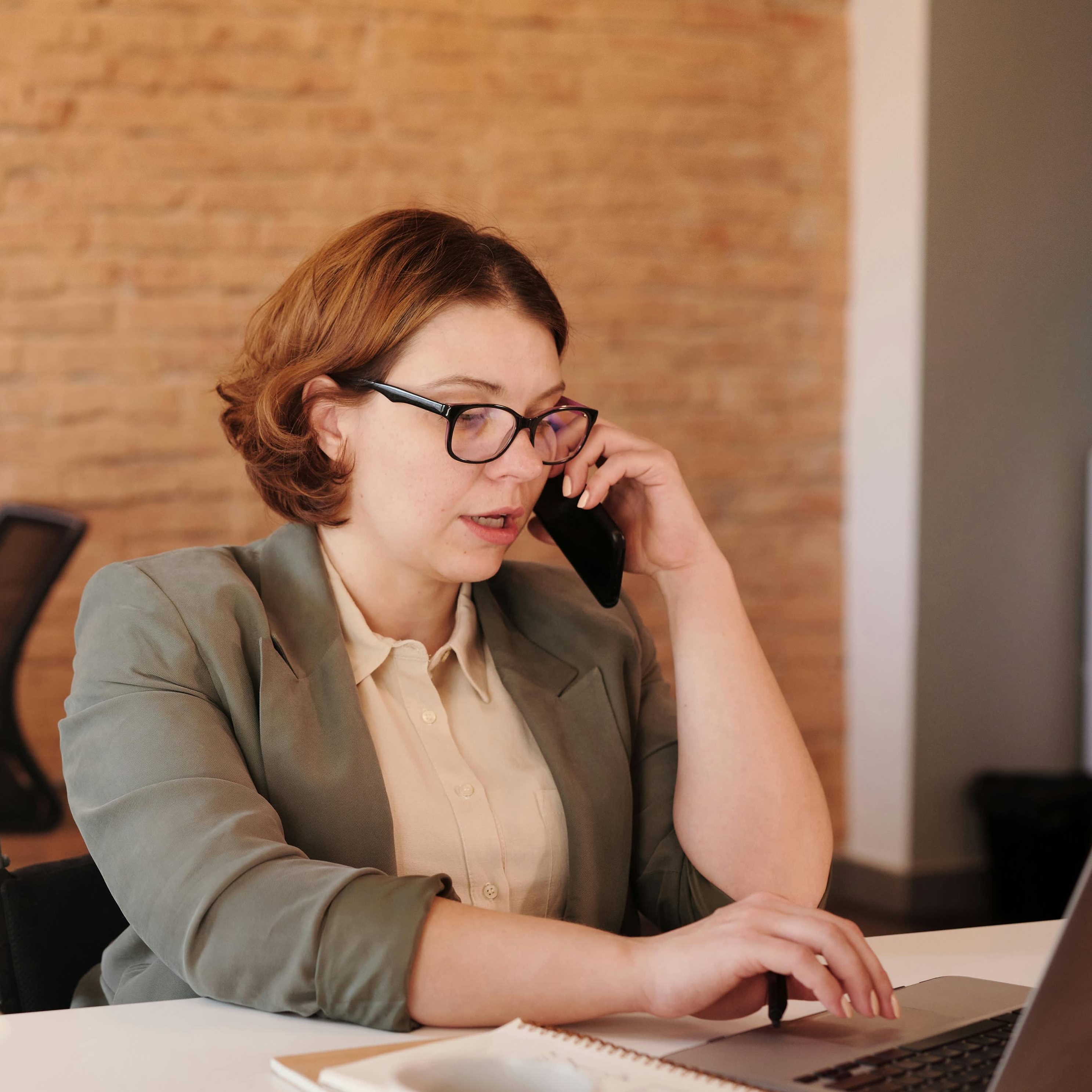 Una mujer atendiendo una llamada en un entorno laboral | Fuente: Pexels