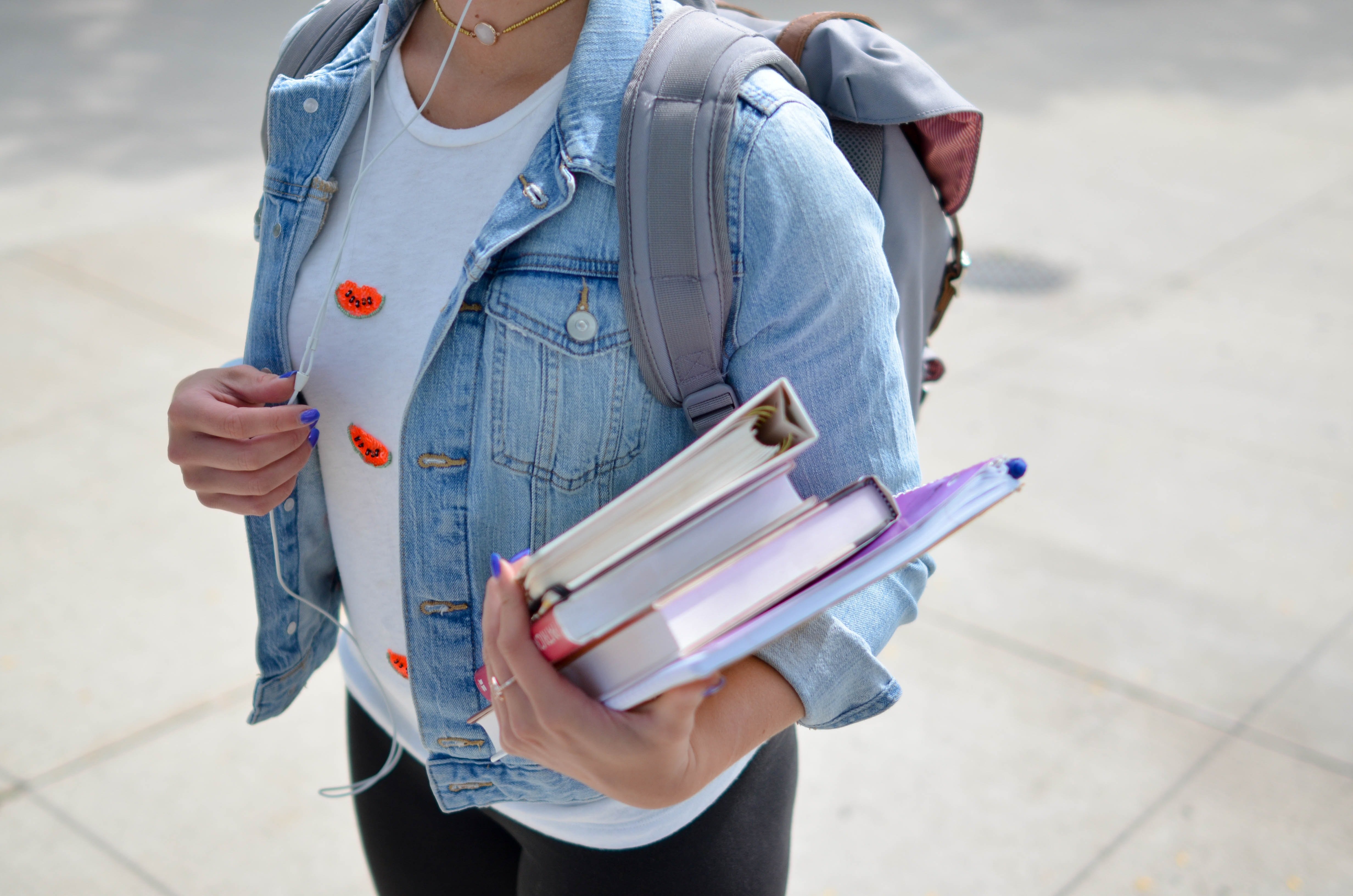 Chica sosteniendo varios libros y una mochila | Foto: Unsplash