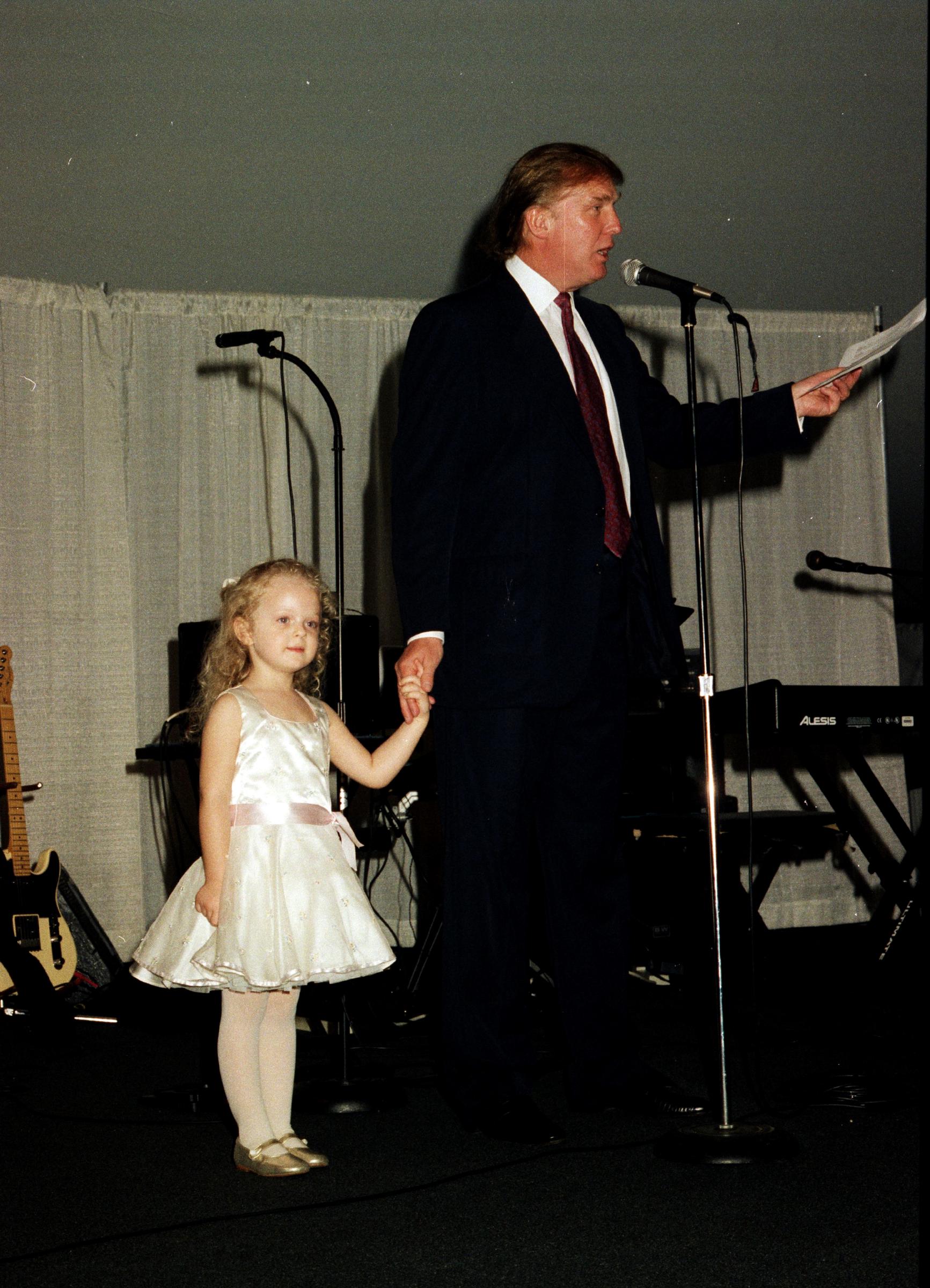 Donald Trump de la mano de su hija mientras habla en el escenario del club Mar-a-Lago en Palm Beach, Florida, el 22 de febrero de 1997 | Fuente: Getty Images