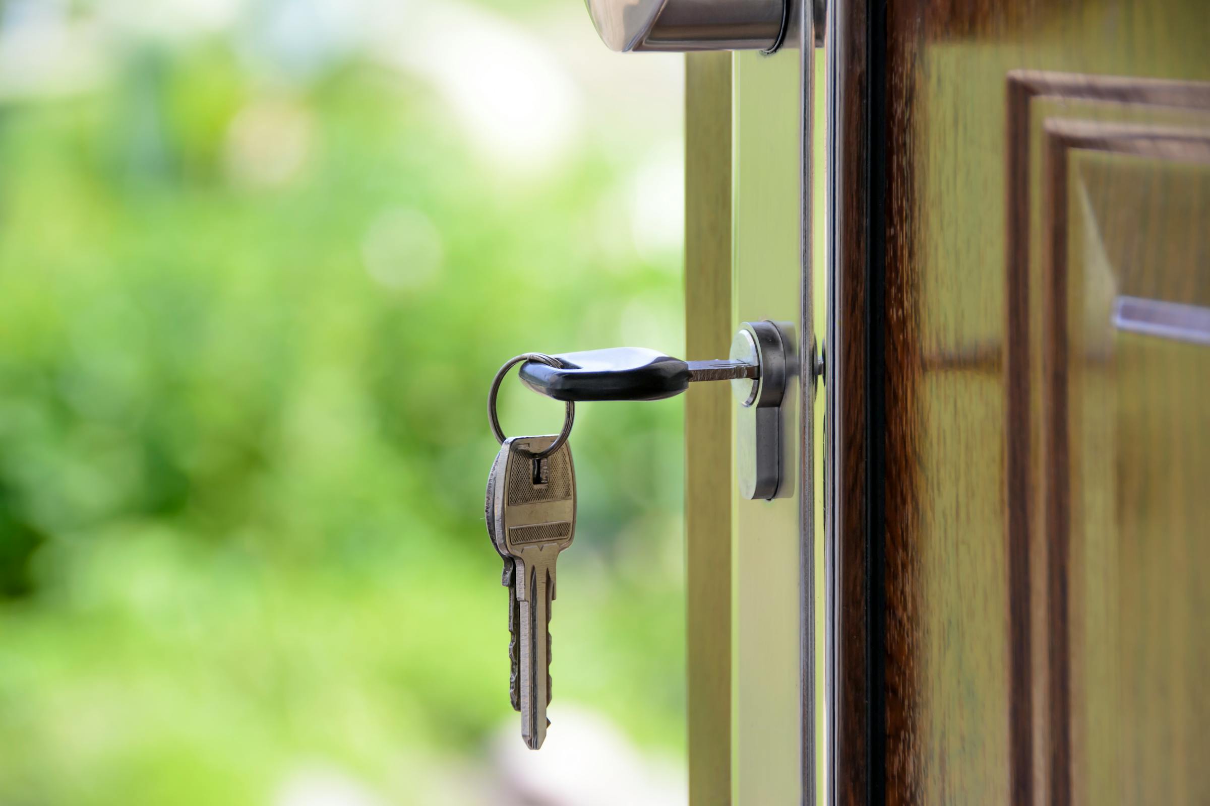 Una llave en la puerta principal de una casa con la puerta abriéndose | Fuente: Pexels