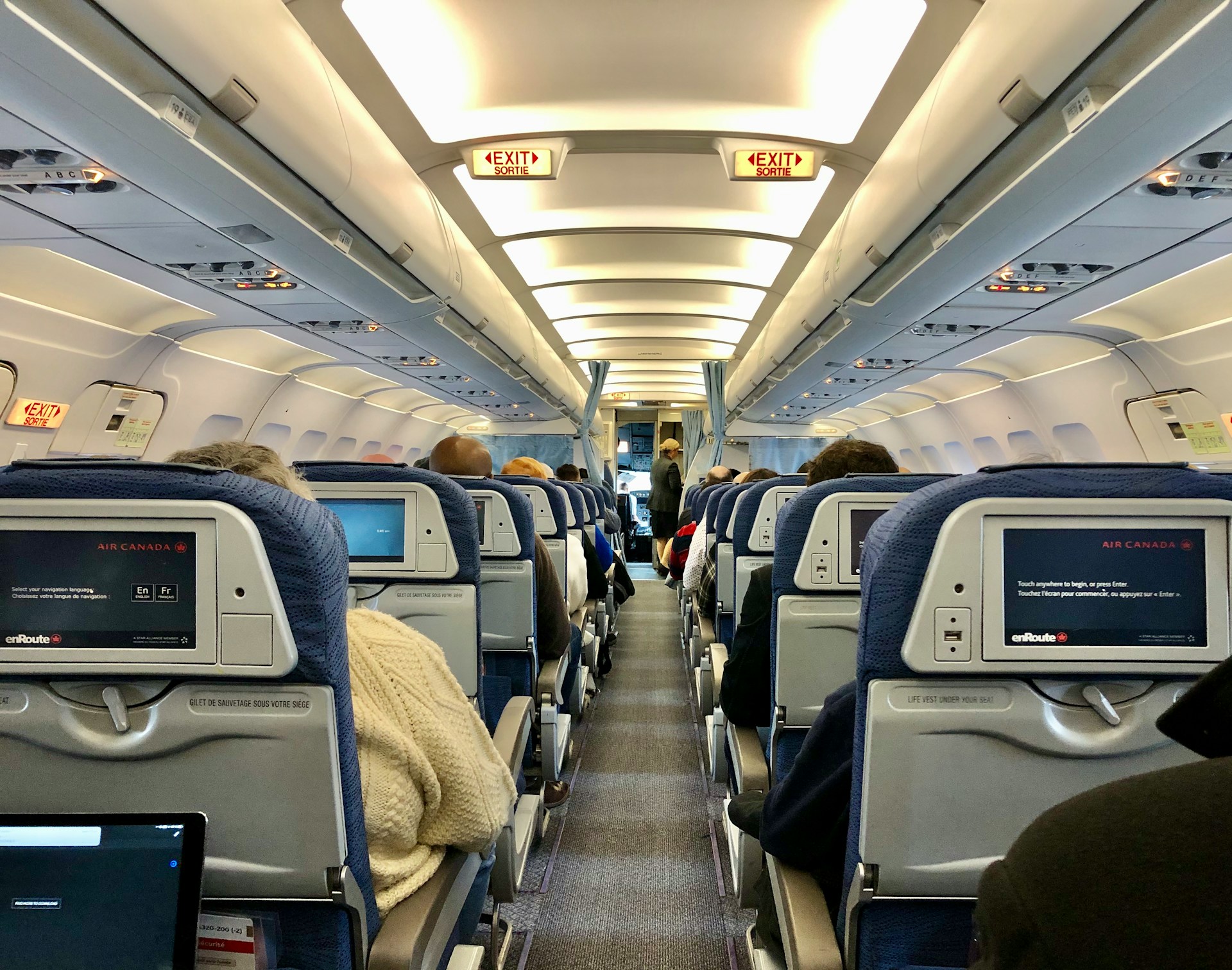 Pasajeros de un vuelo sentados en el pasillo de clase turista | Fuente: Unsplash