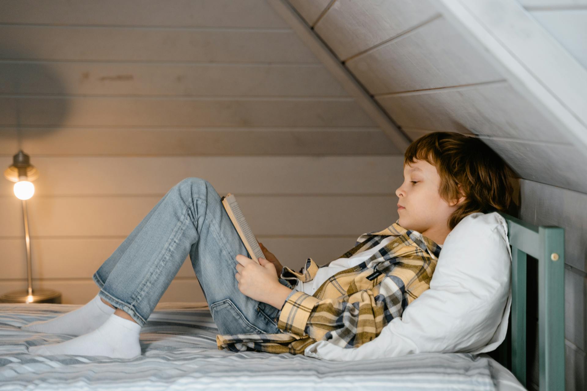 Un niño leyendo en su cama | Fuente: Pexels