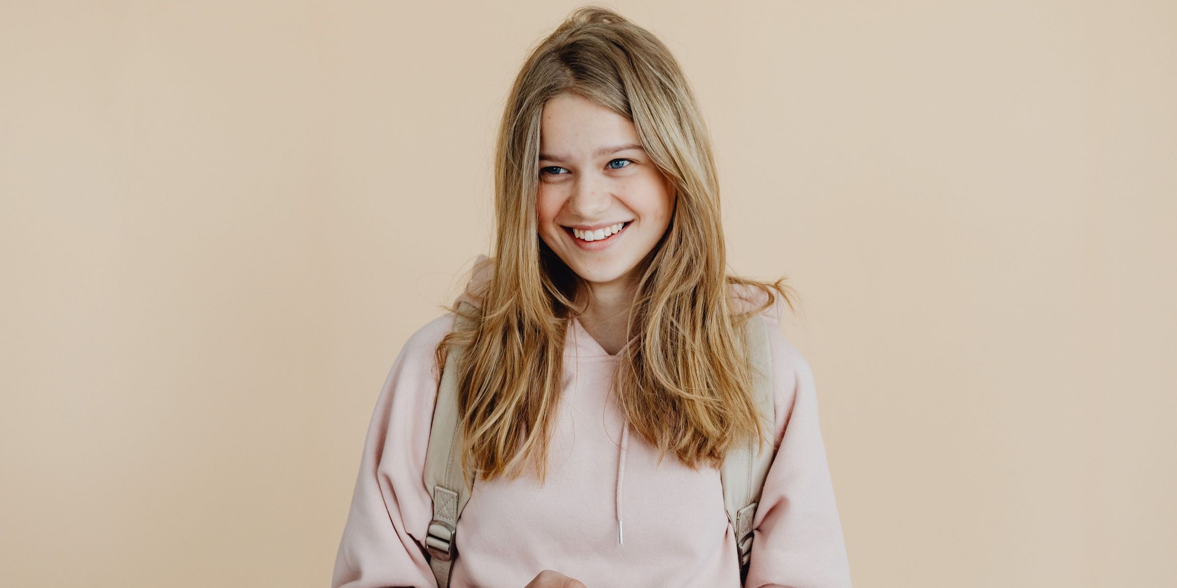 Una chica joven y sonriente con una sudadera rosa con capucha | Fuente: Pexels