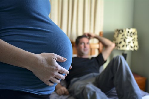 Esposo mira desde la cama a su esposa embarazada. | Foto: Shutterstock