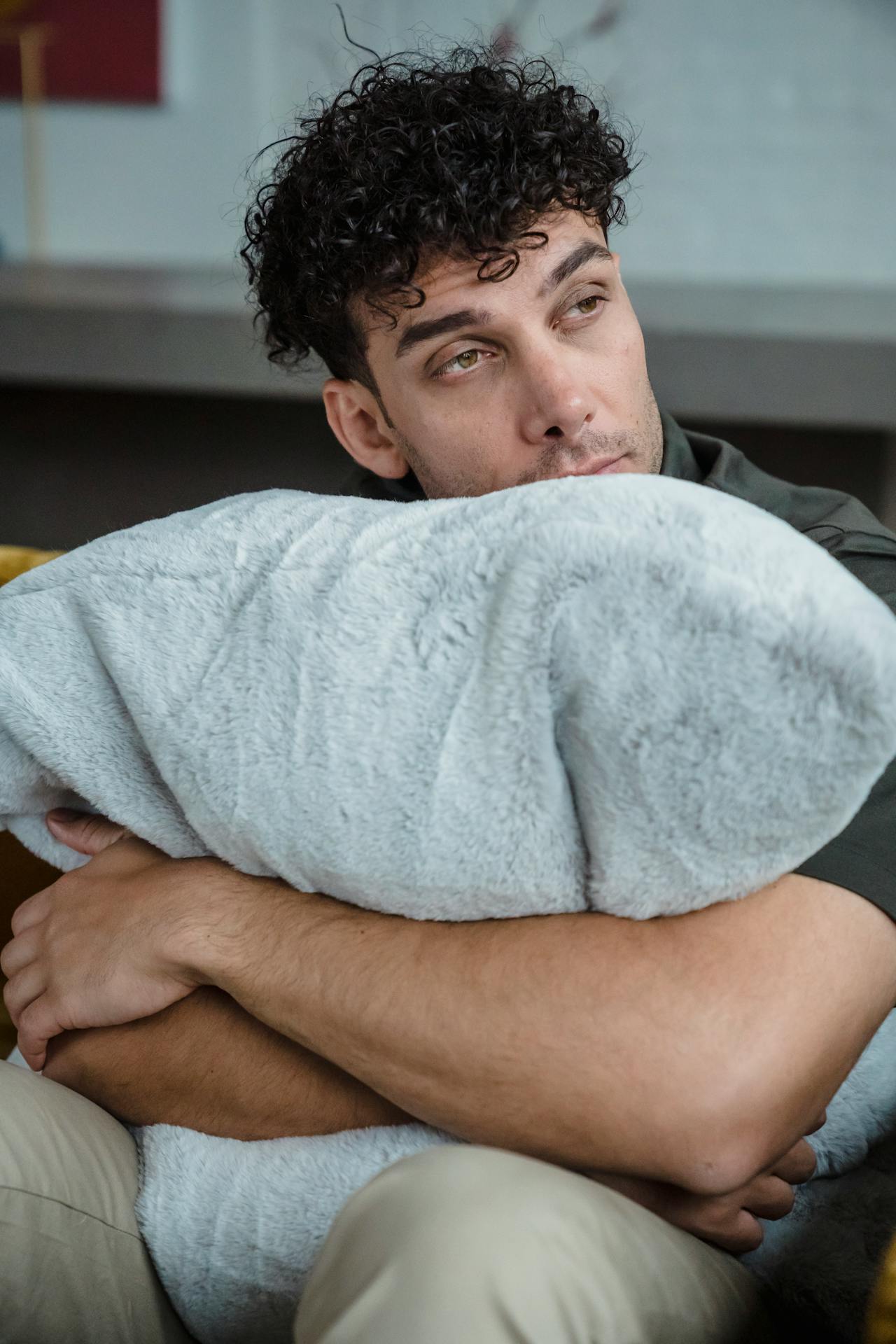 Un hombre abrazando su almohada y mirando fijamente a alguien | Fuente: Pexels
