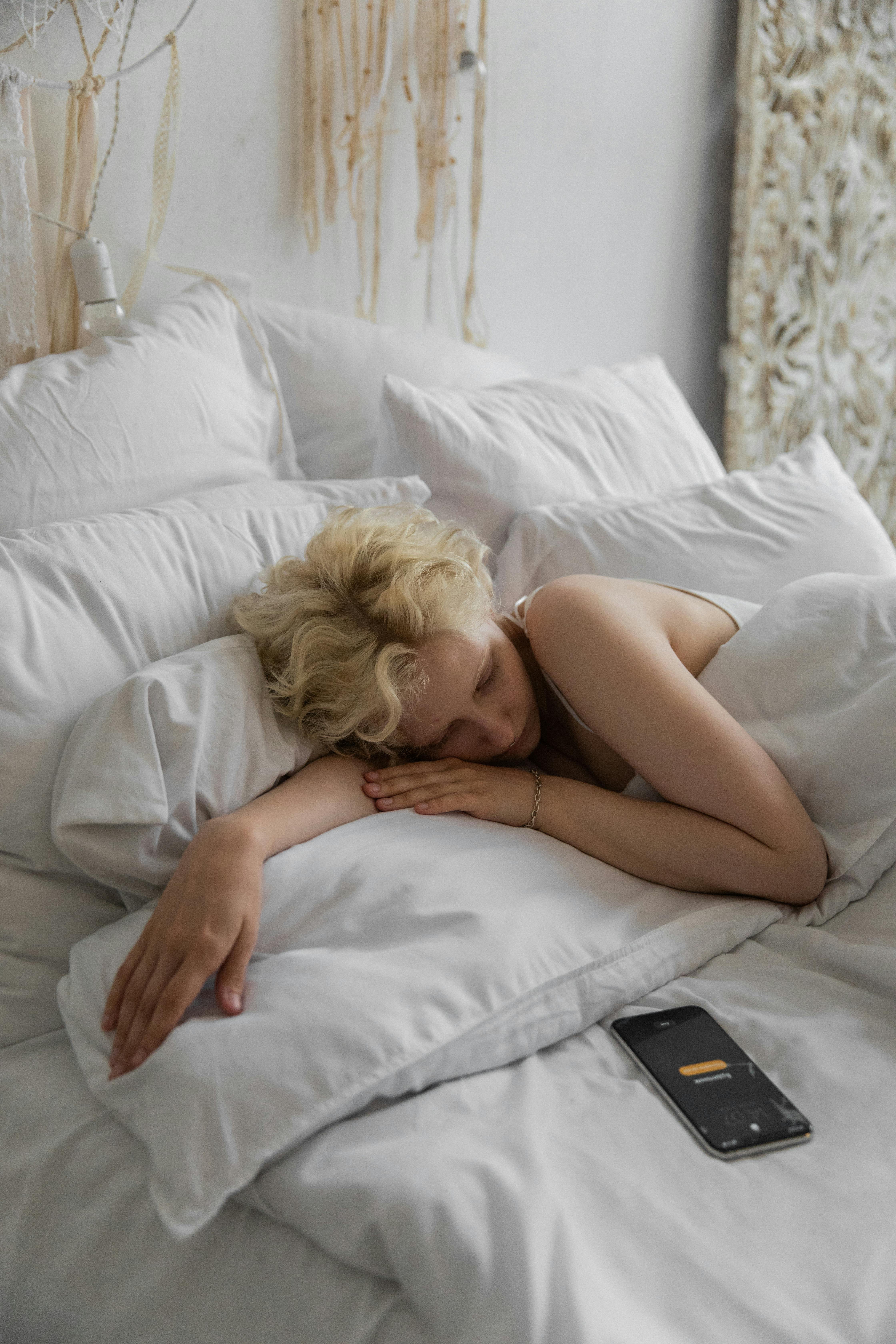 Una mujer en la cama con el teléfono desatendido | Foto: Pexels