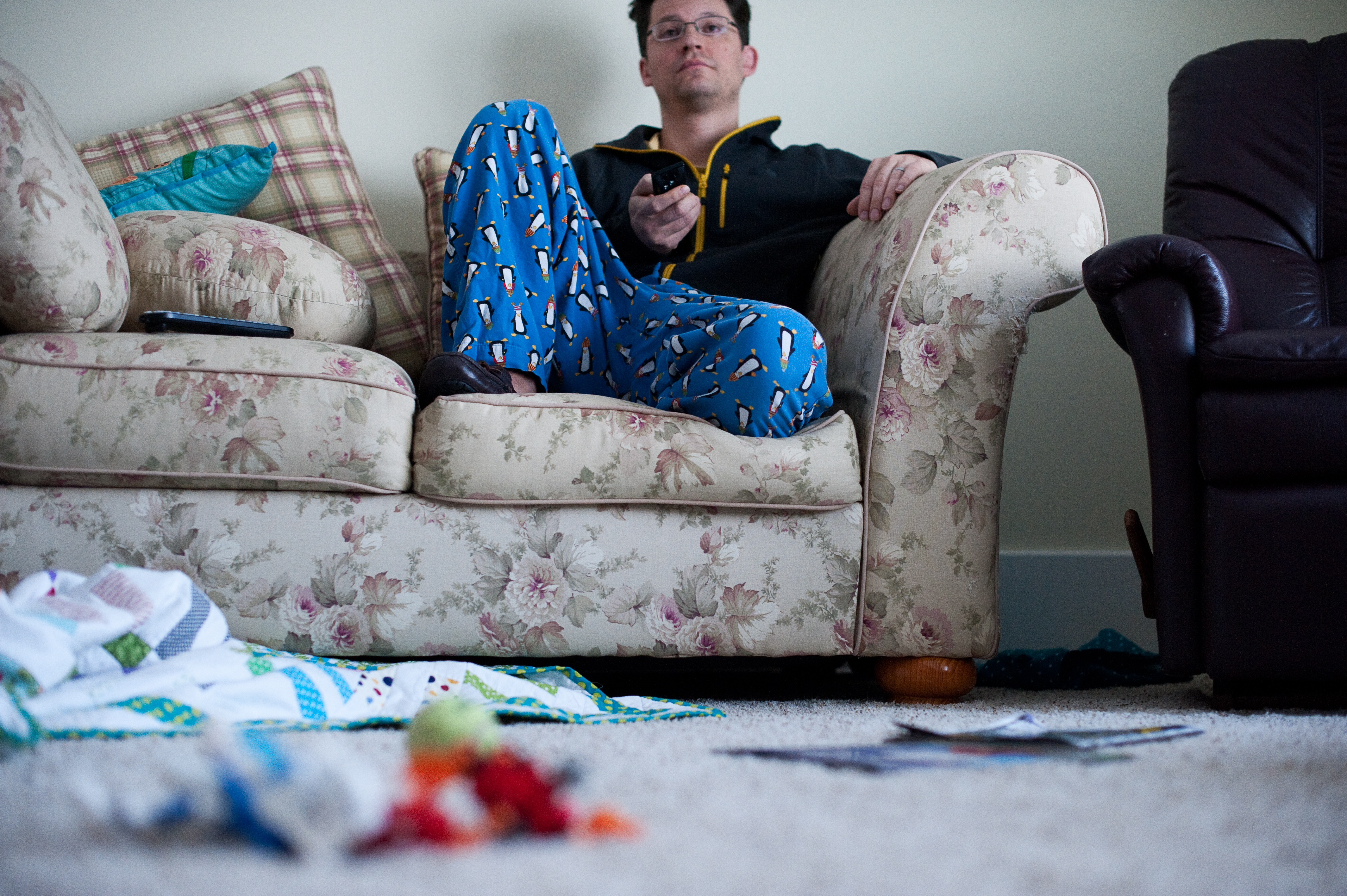 Un perezoso sentado viendo la televisión con la casa desordenada | Fuente: Getty Images