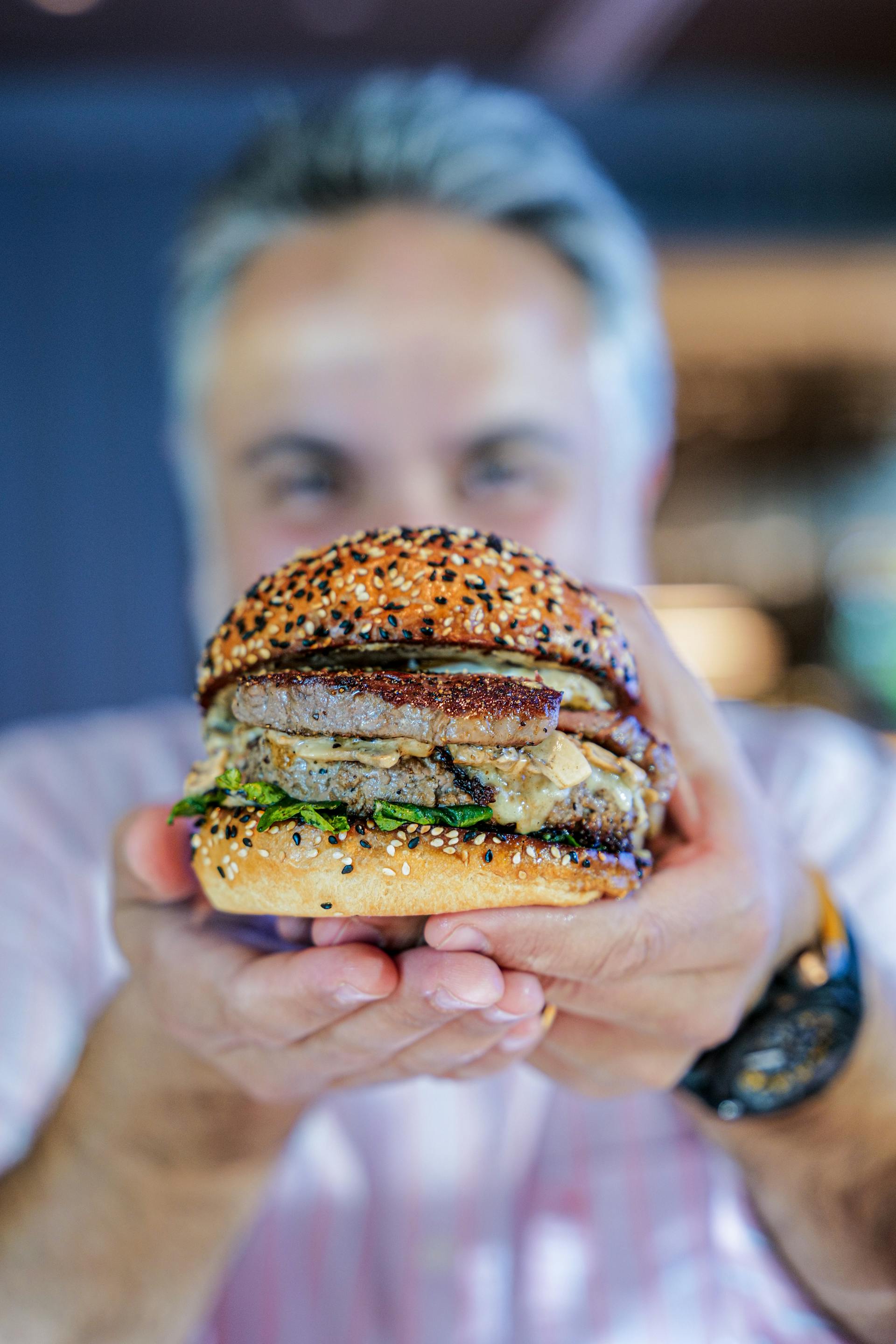 Un hombre sujetando una hamburguesa | Fuente: Pexels