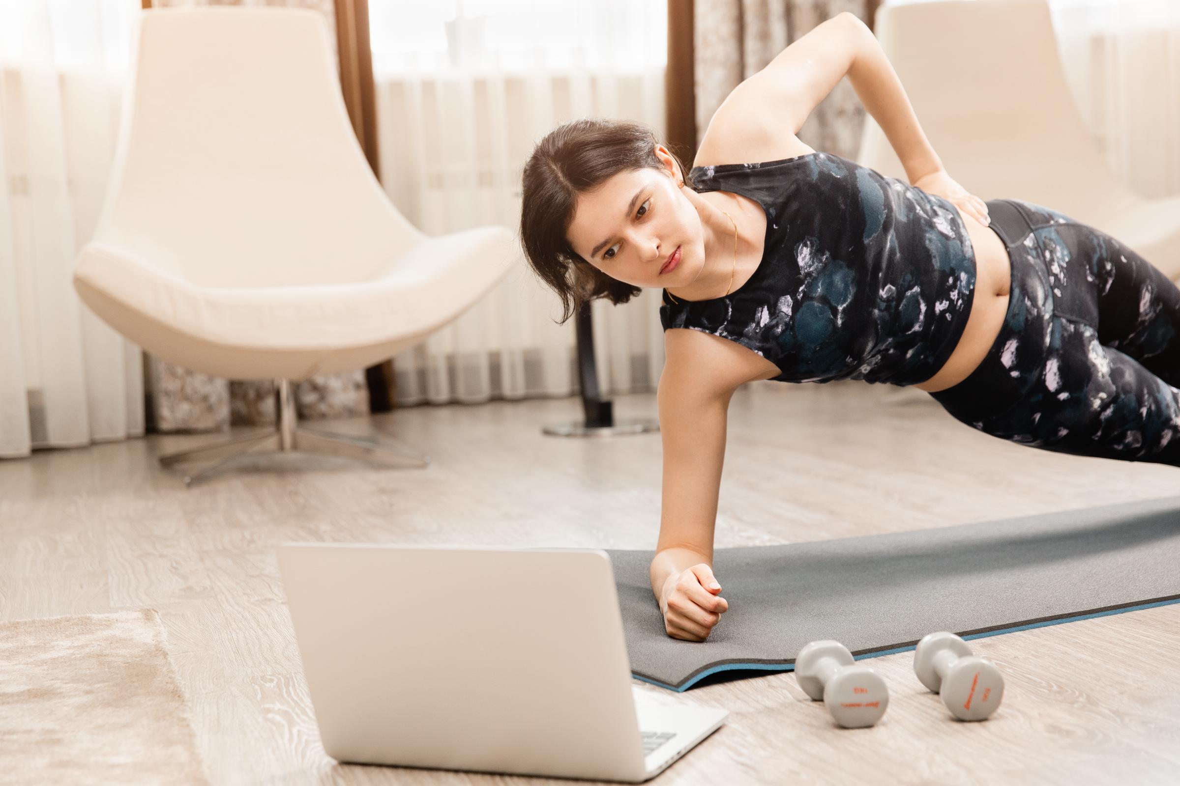 Mujer haciendo ejercicio en línea en casa | Fuente: Shutterstock