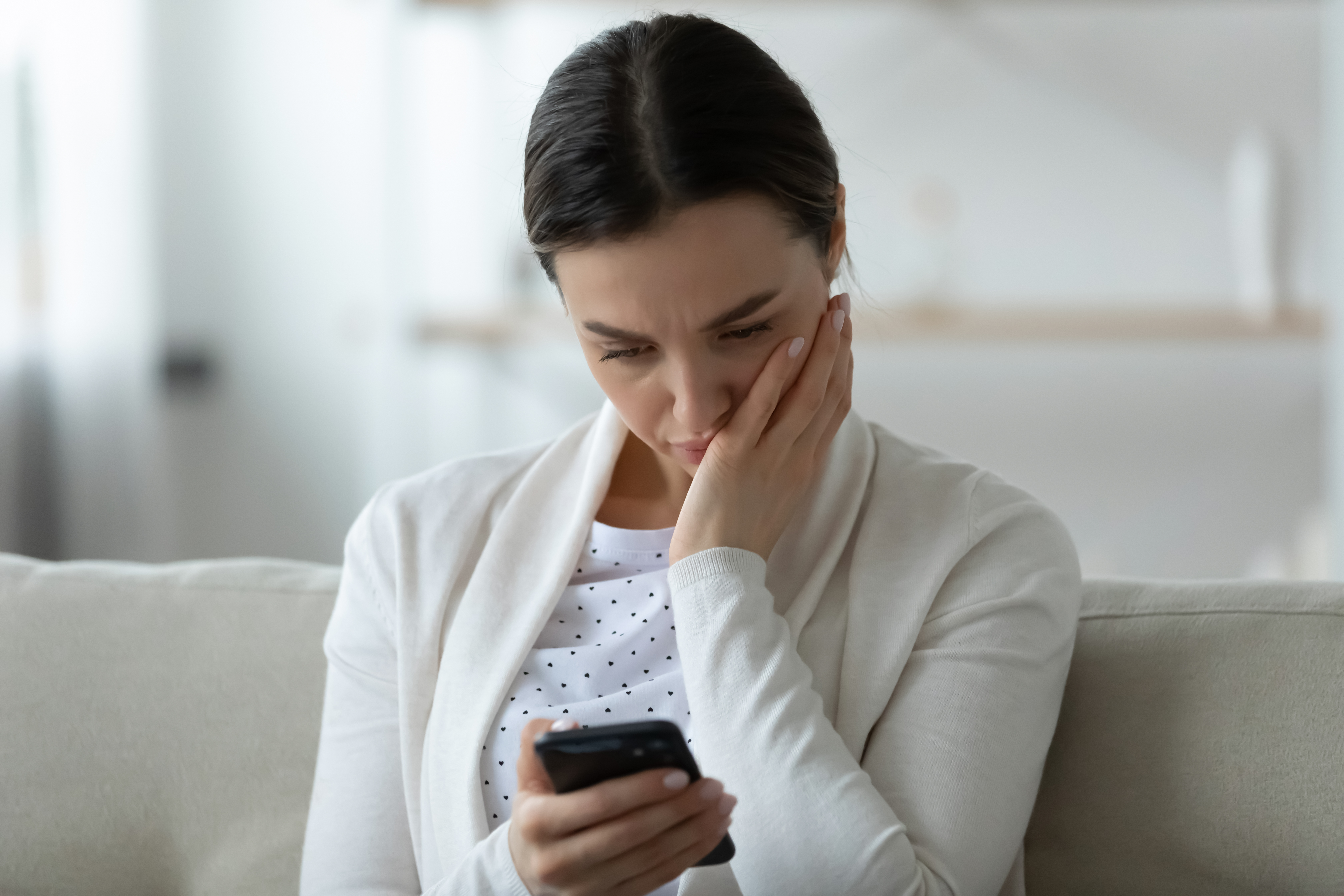 Una mujer angustiada mirando la pantalla de su teléfono | Fuente: Shutterstock