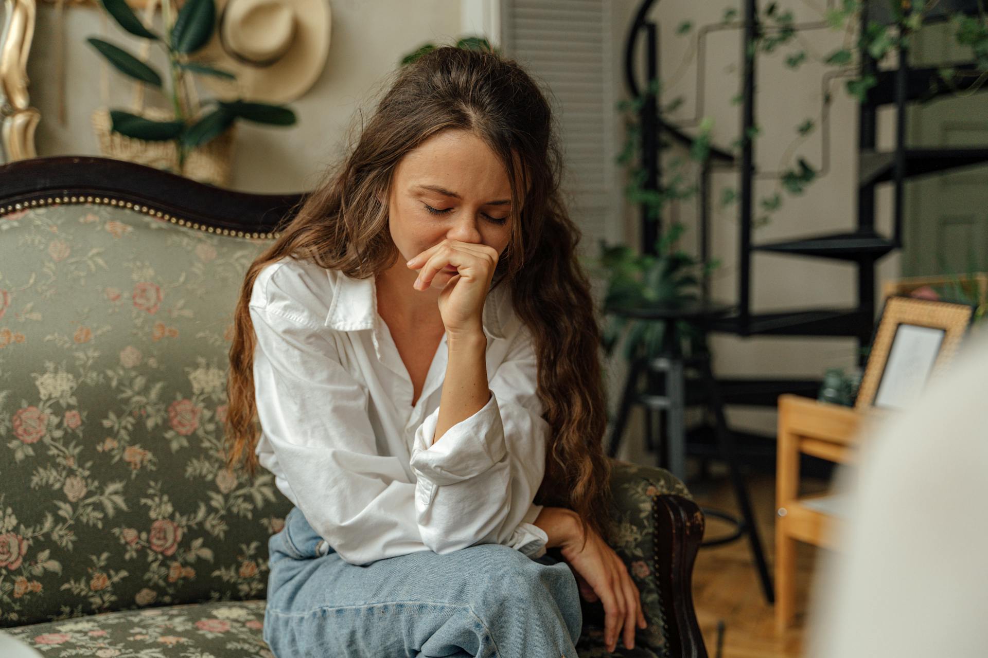 Una donna emotiva su un divano | Fonte: Pexels