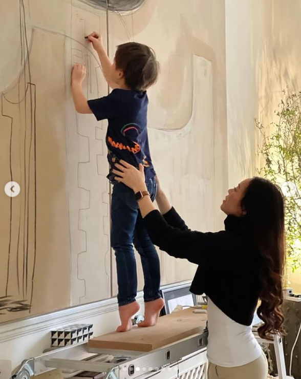 Christopher Woolf Mapelli Mozzi muestra sus dotes artísticas, dibujando en un retrato mientras su madre, Dara Huang, le sujeta por detrás. | Foto: Instagram/dara_huang