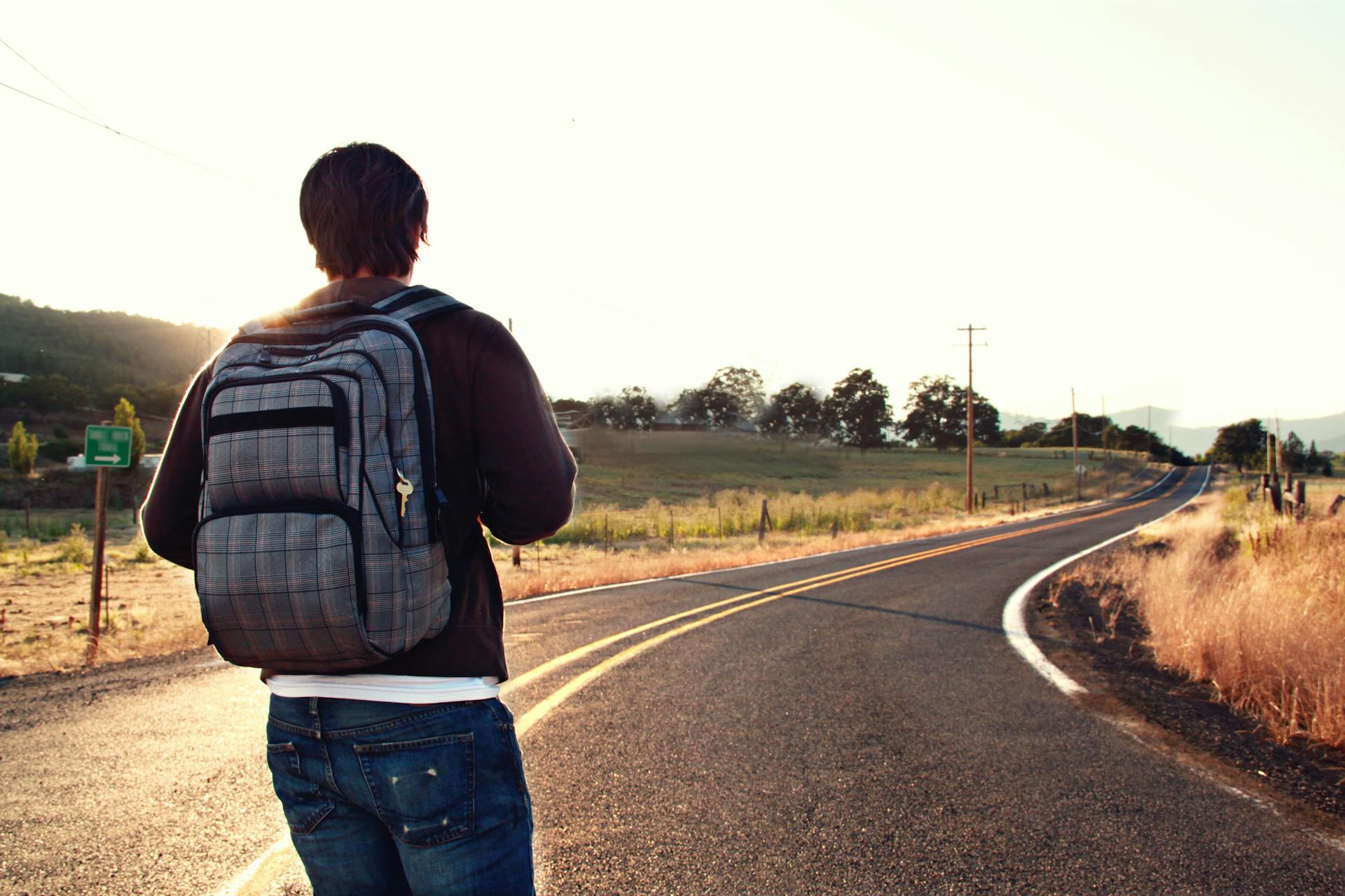 Un hombre con una mochila de pie en una carretera | Fuente: Pexels