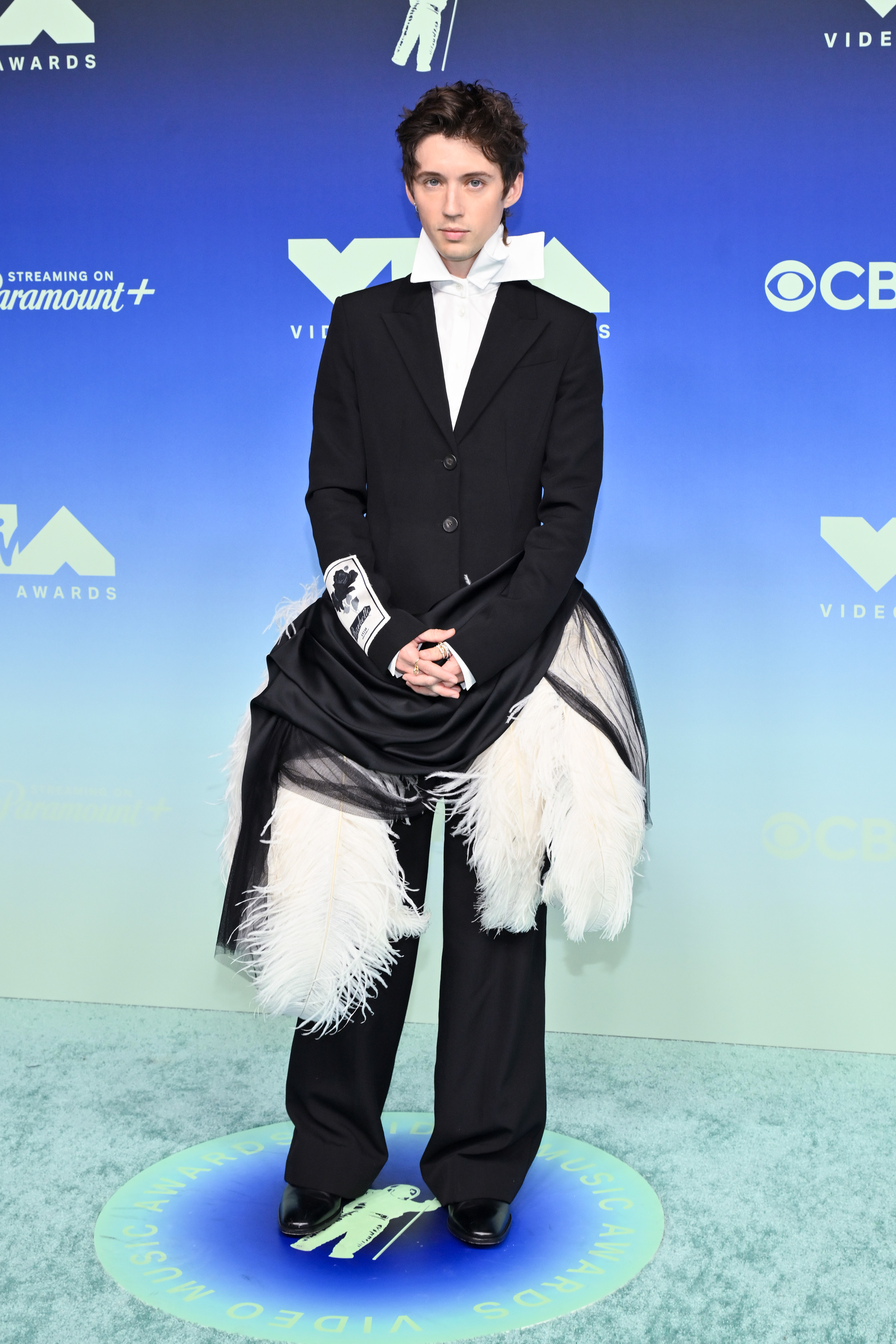 Sivan le dio un toque diferente al clásico traje negro con un lazo blanco oversize y grandes paneles con plumas alrededor de los muslos. La tela negra drapeada en la cintura añadía otra capa entre la chaqueta entallada y los pantalones holgados. | Fuente: Getty Images