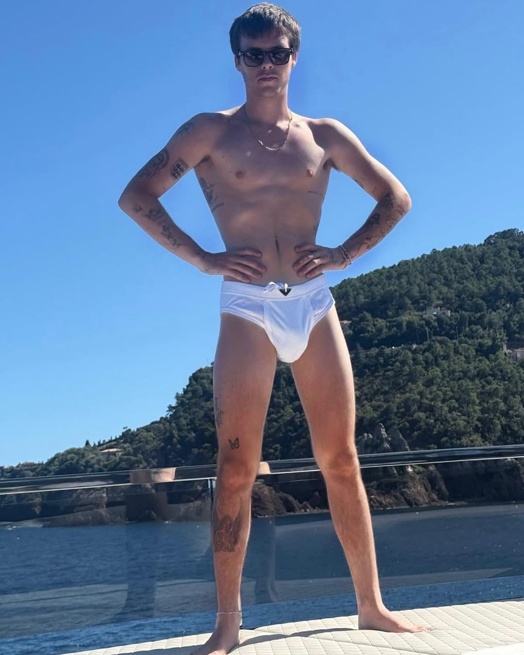 Cruz Beckham de pie en un yate con un bañador, del post sobre las vacaciones de Victoria Beckham del 10 de agosto de 2025 | Fuente: Instagram/victoriabeckham