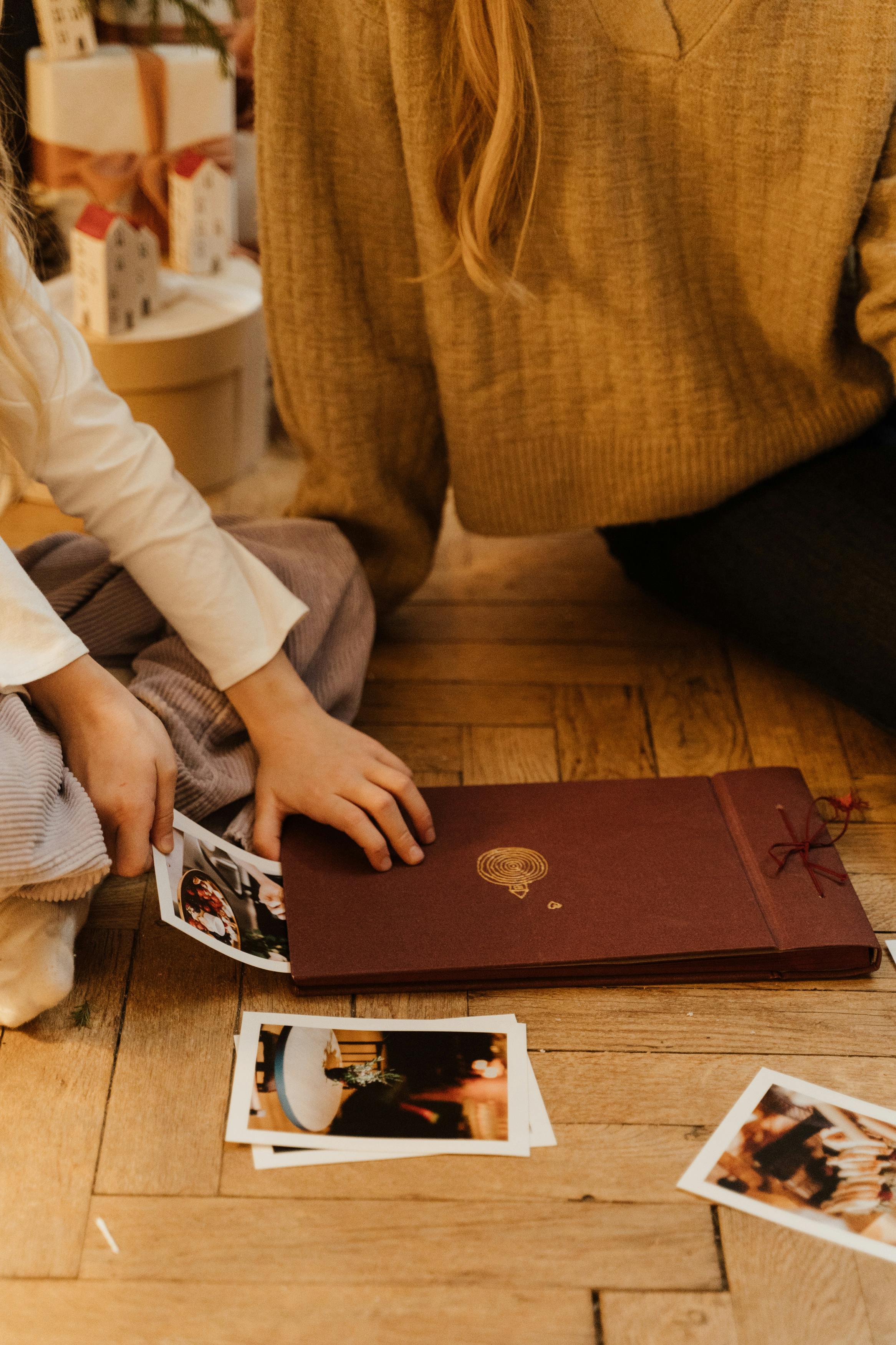 Un niño sacando fotos de un libro con un adulto sentado a su lado | Fuente: Pexels