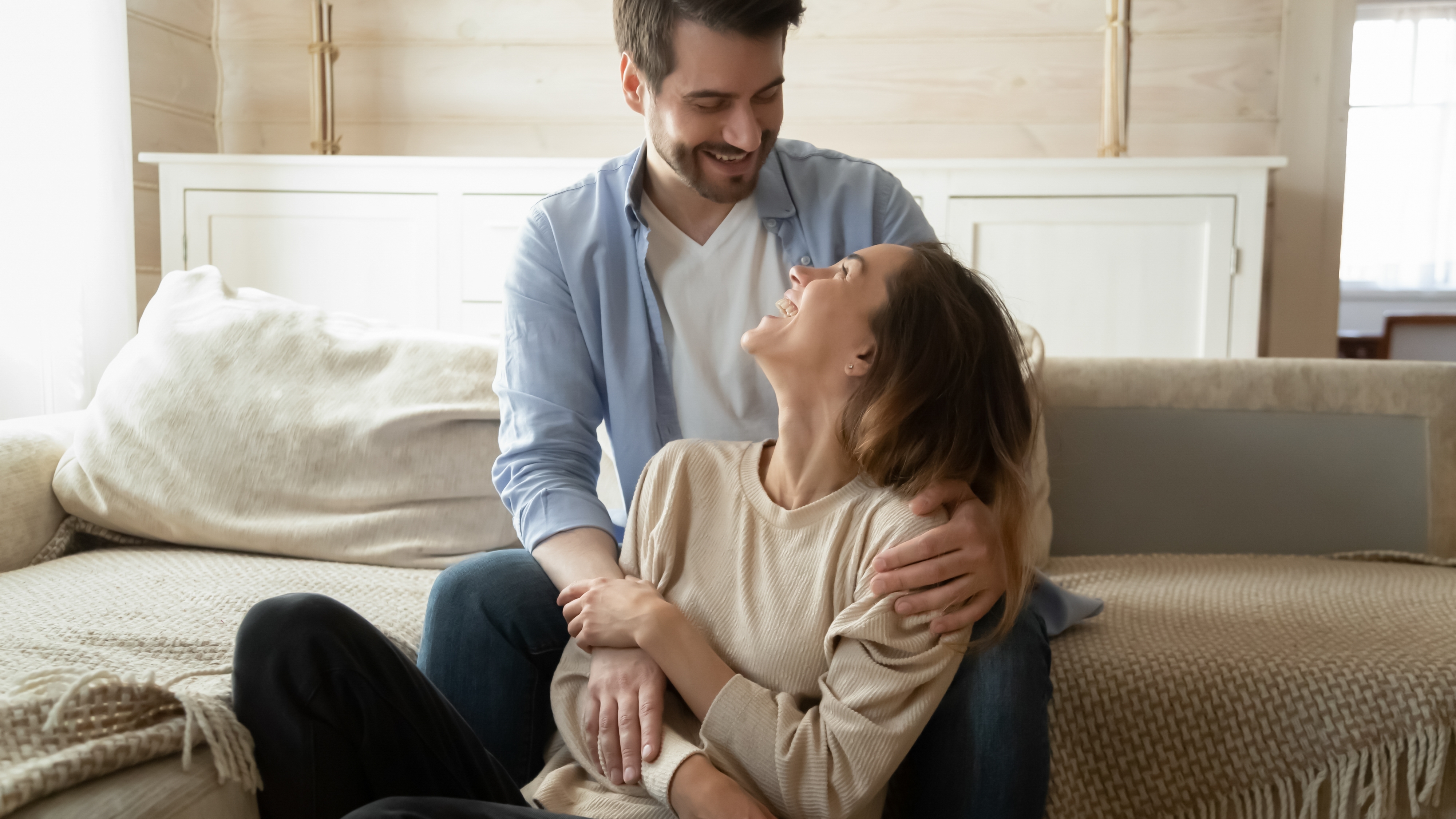 Una pareja cogida de la mano y abrazándose en casa | Fuente: Shutterstock