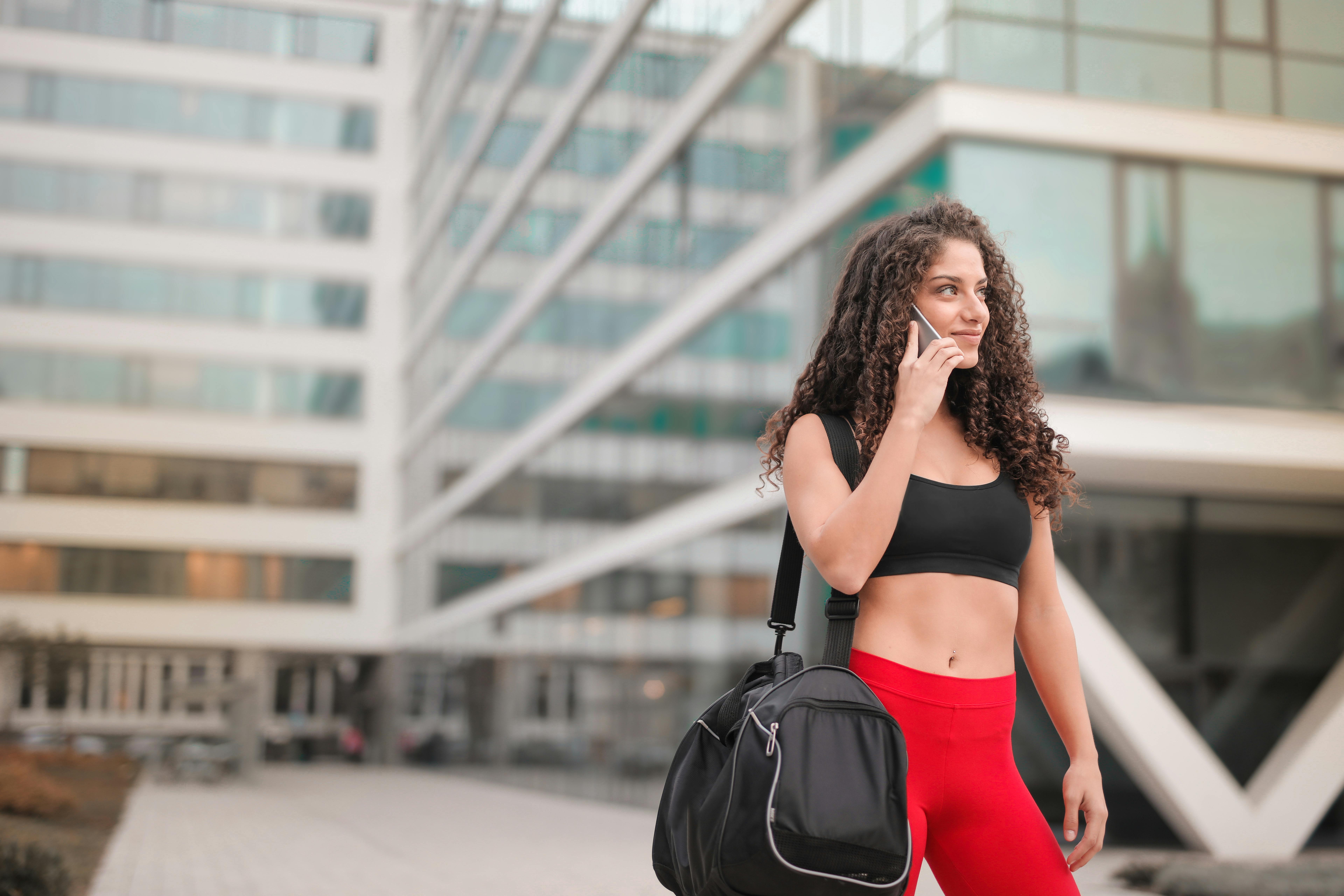 Una mujer con ropa de gimnasia acercándose el teléfono a la oreja | Fuente: Pexels