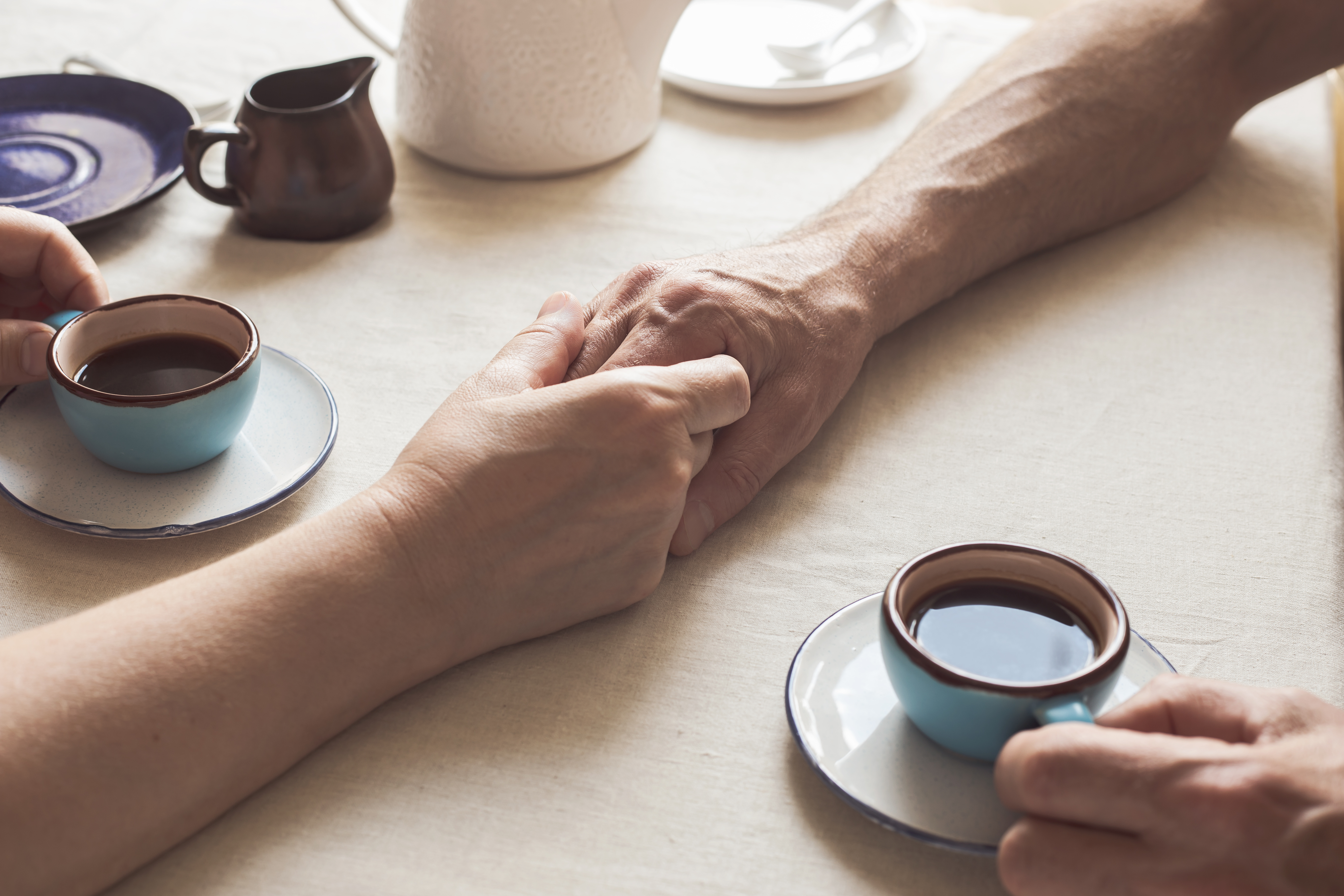 Una pareja de ancianos cogidos de la mano y tomando café | Foto: Getty Images