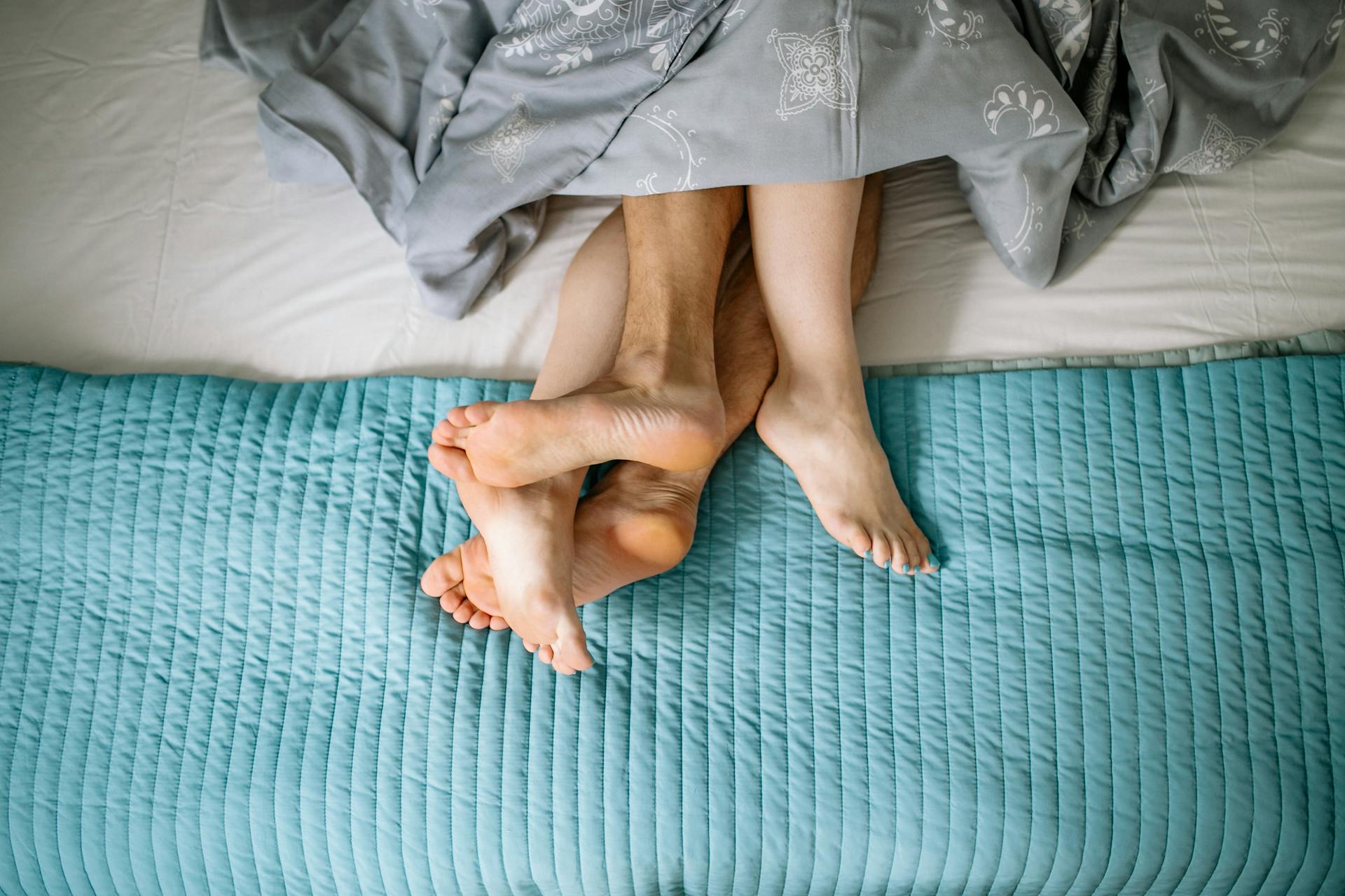 Primer plano de las piernas de una pareja entrelazadas en la cama | Fuente: Pexels