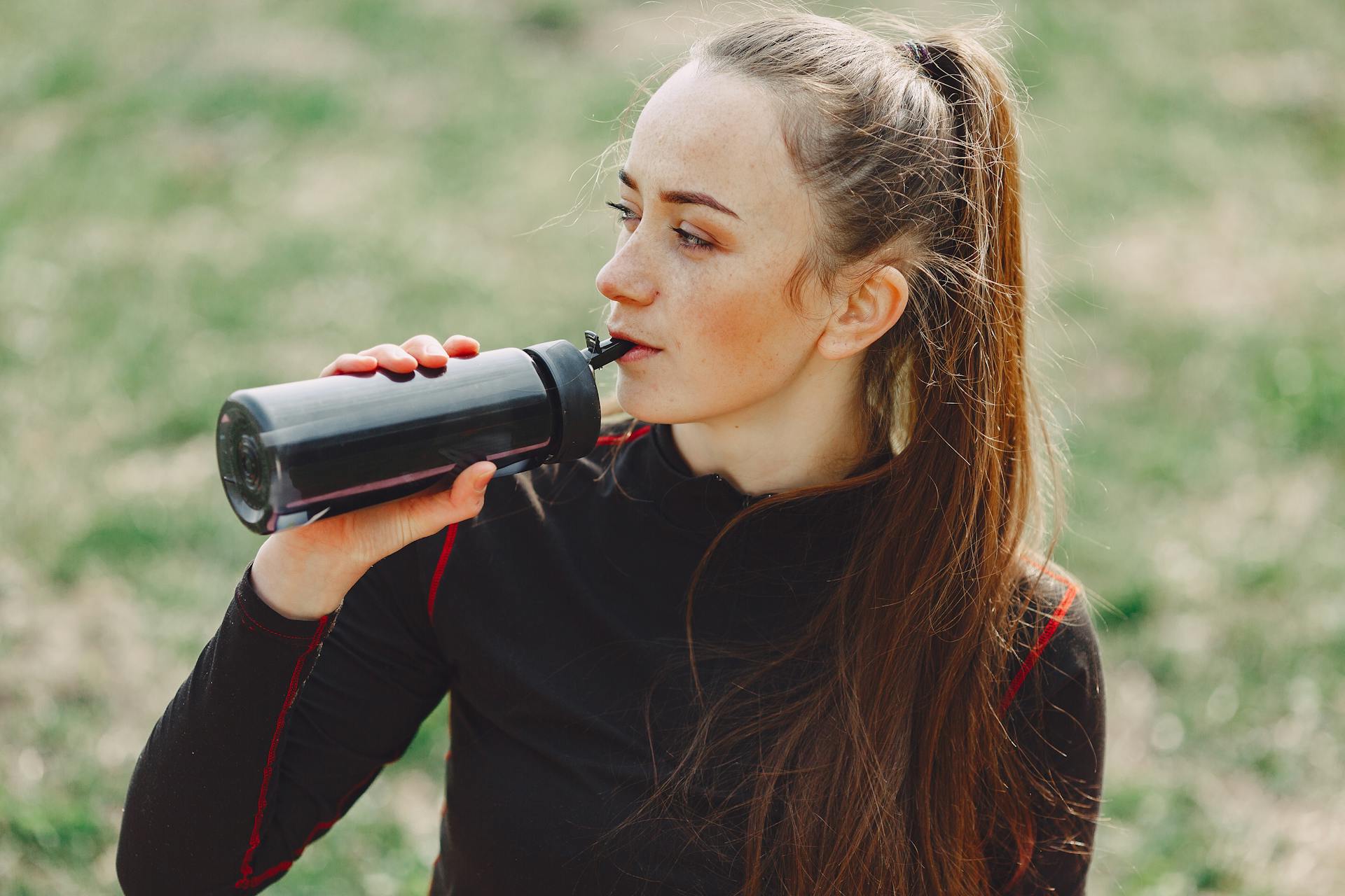 Una mujer bebiendo agua de una botella | Foto: Pexels