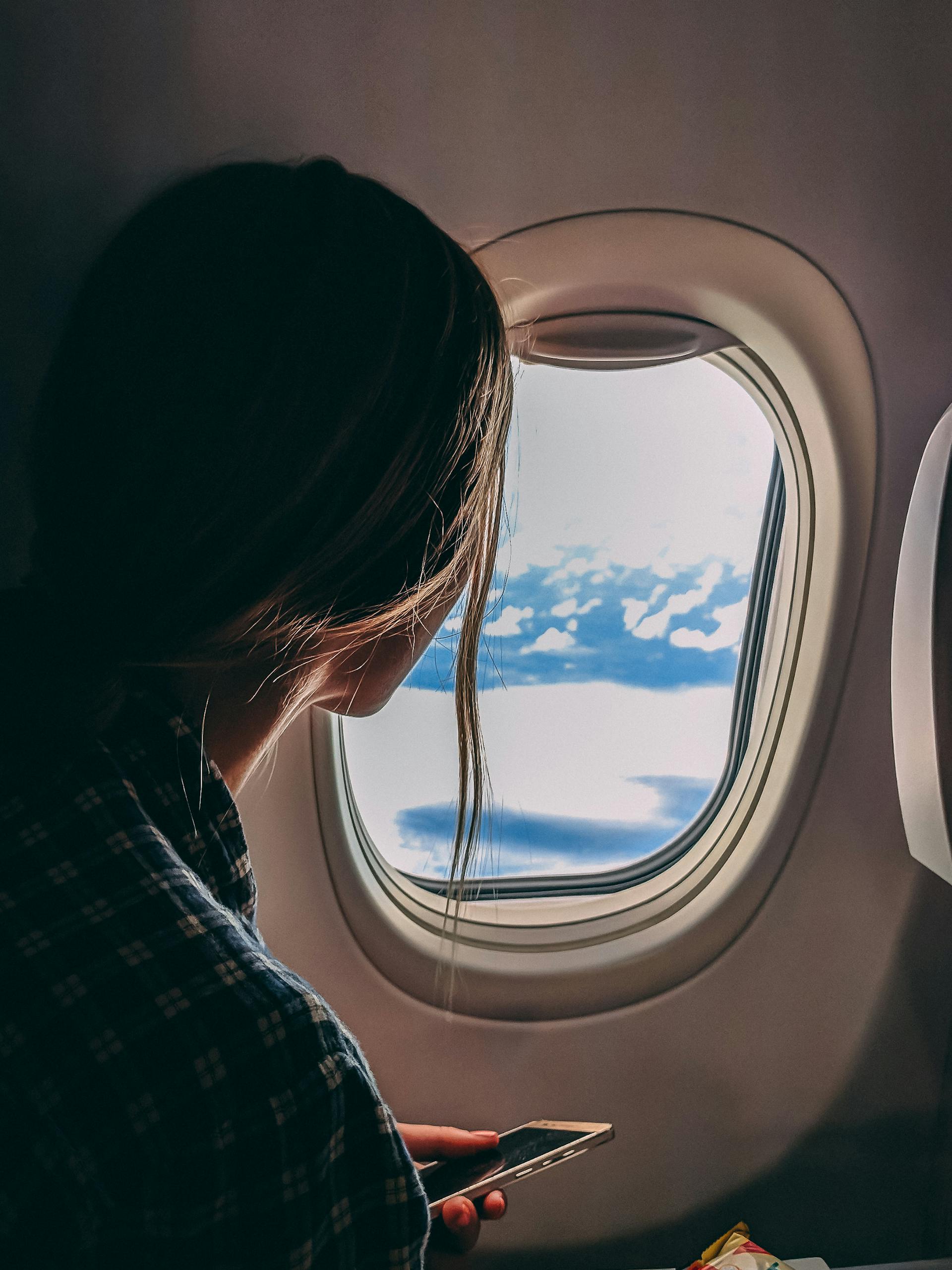 Una mujer sostiene su smartphone mientras viaja en avión | Fuente: Pexels