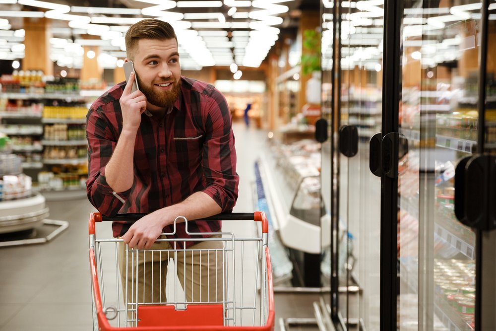 Hombre llamando por teléfono desde el supermercado. | Foto: Shutterstock.