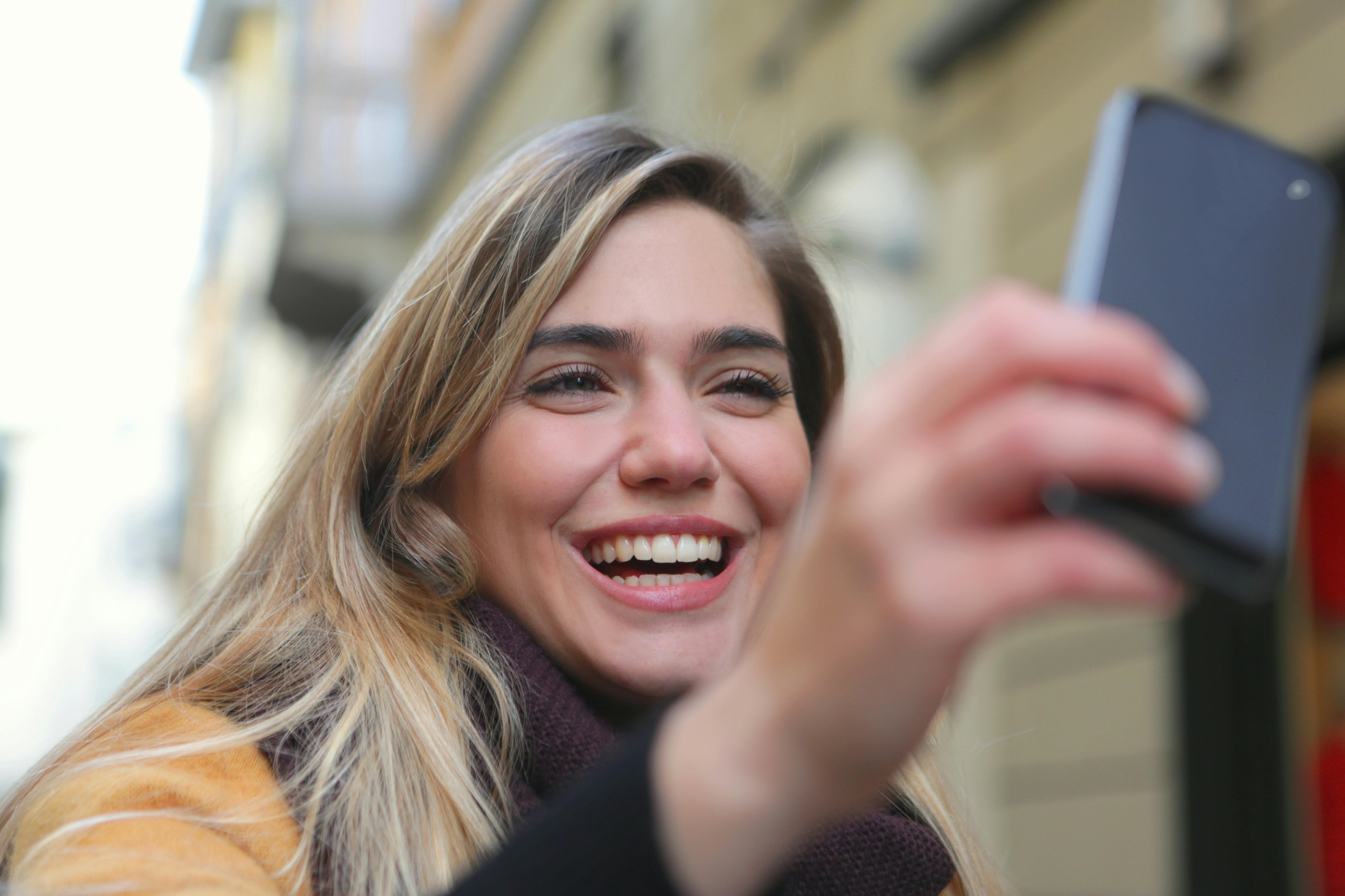 Una mujer riendo mientras mira su teléfono | Fuente: Pexels