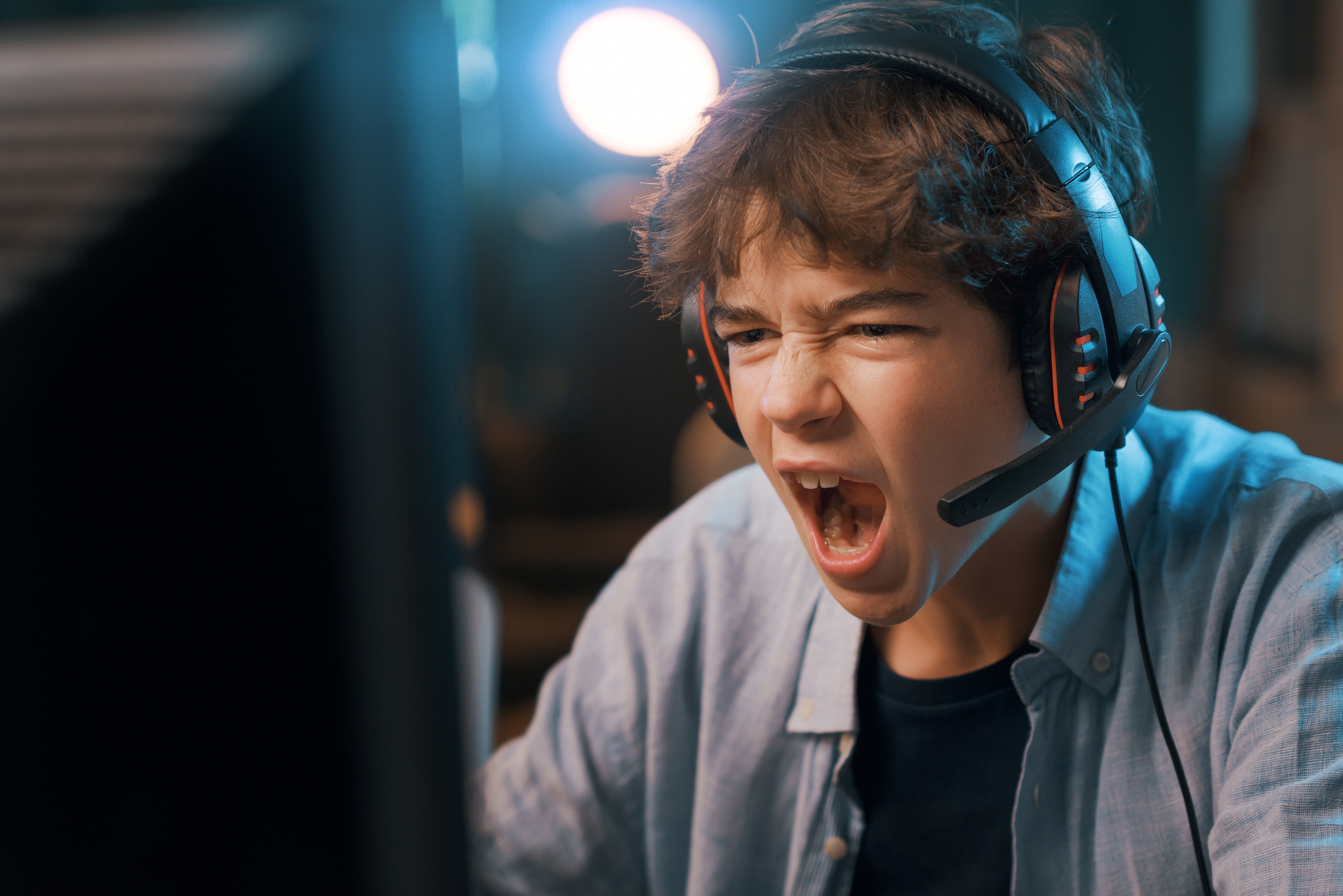 Un chico enfadado gritando a los auriculares de su ordenador. │ Foto: Shutterstock