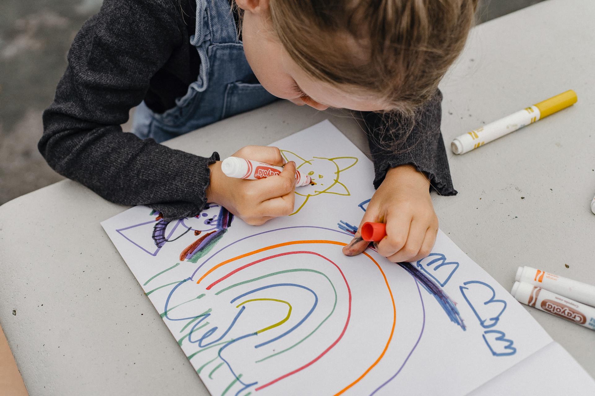 Un primo piano di una bambina che disegna con i pennarelli su un foglio di carta | Fonte: Pexels