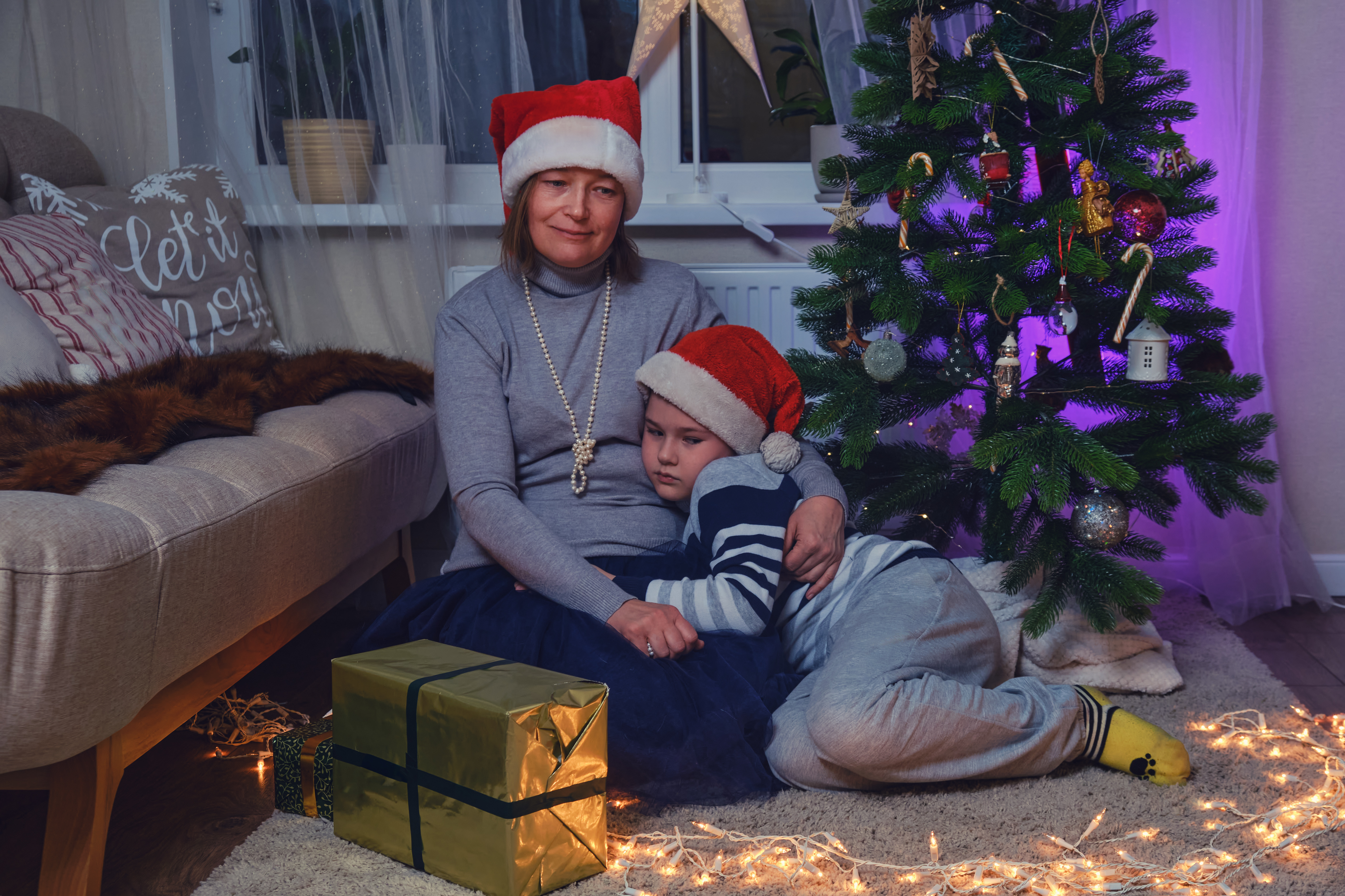 Madre e hijo sentados cerca del árbol de Navidad | Foto: Getty Images