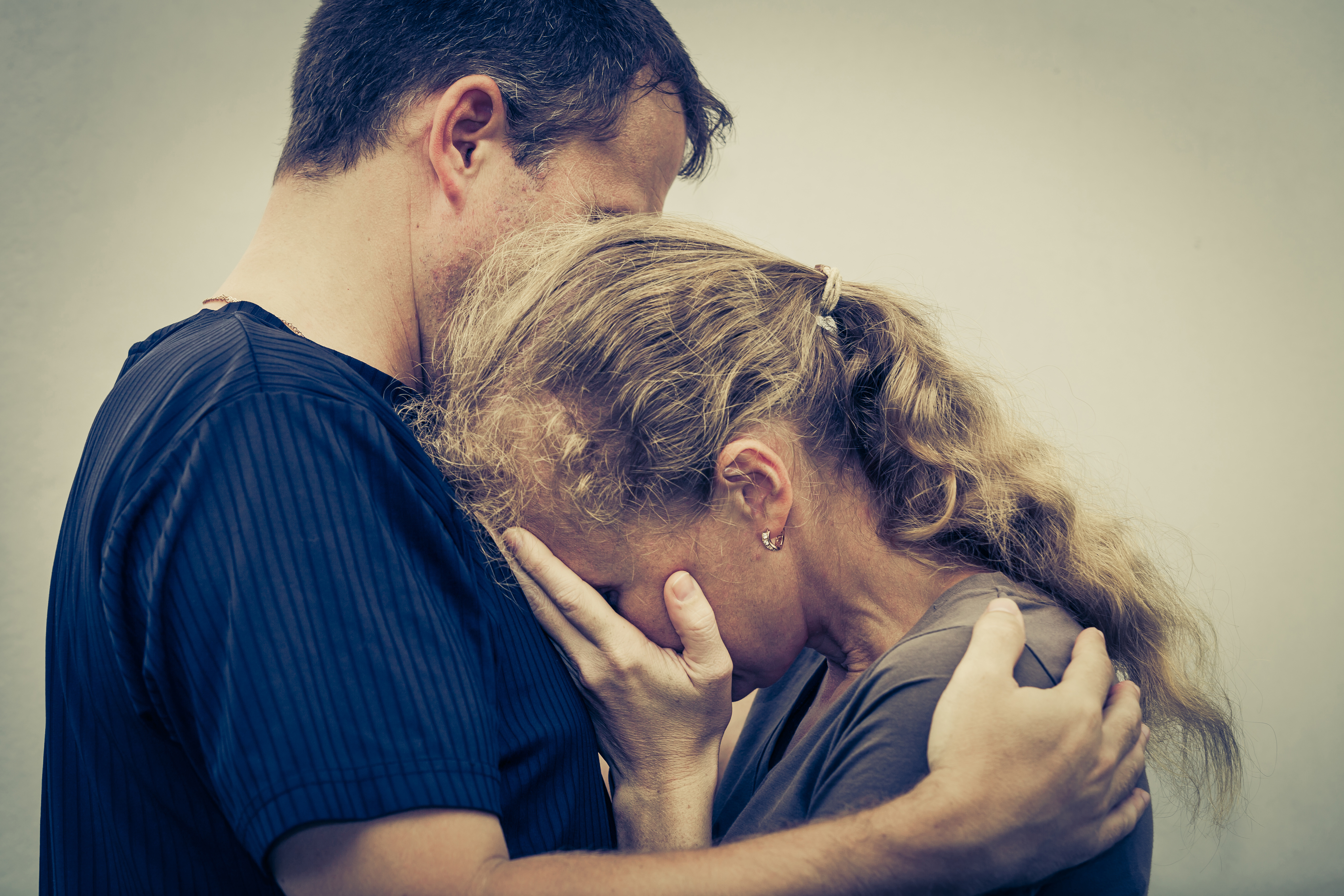 Una mujer llorando abraza a su marido | Foto: Shutterstock