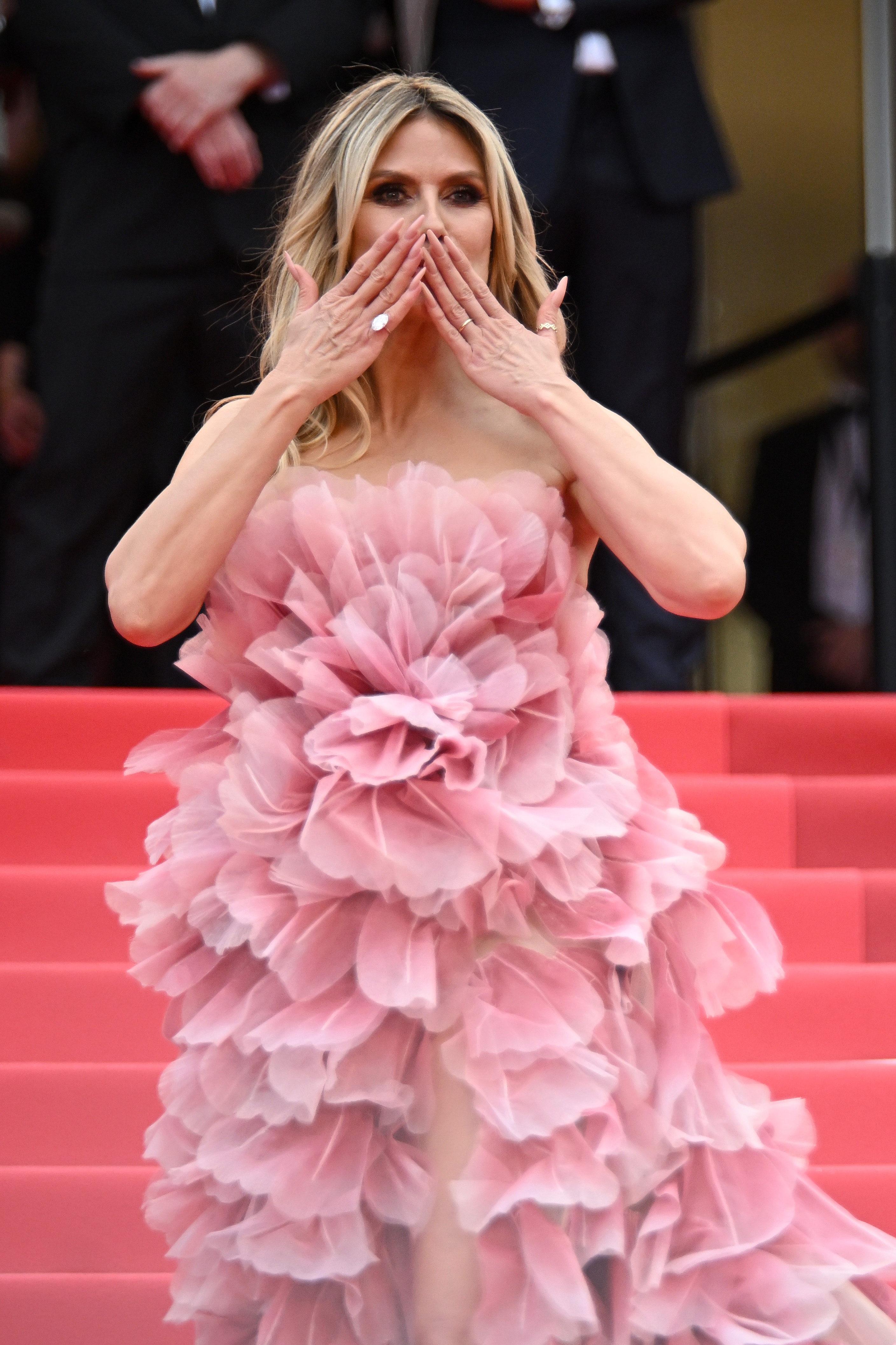 Incluso después de saltarse las normas, Klum irradia alegría en la alfombra roja: fotografiada en medio de un juguetón beso, presume de uñas cuidadas y anillos relucientes, disfrutando claramente del momento.