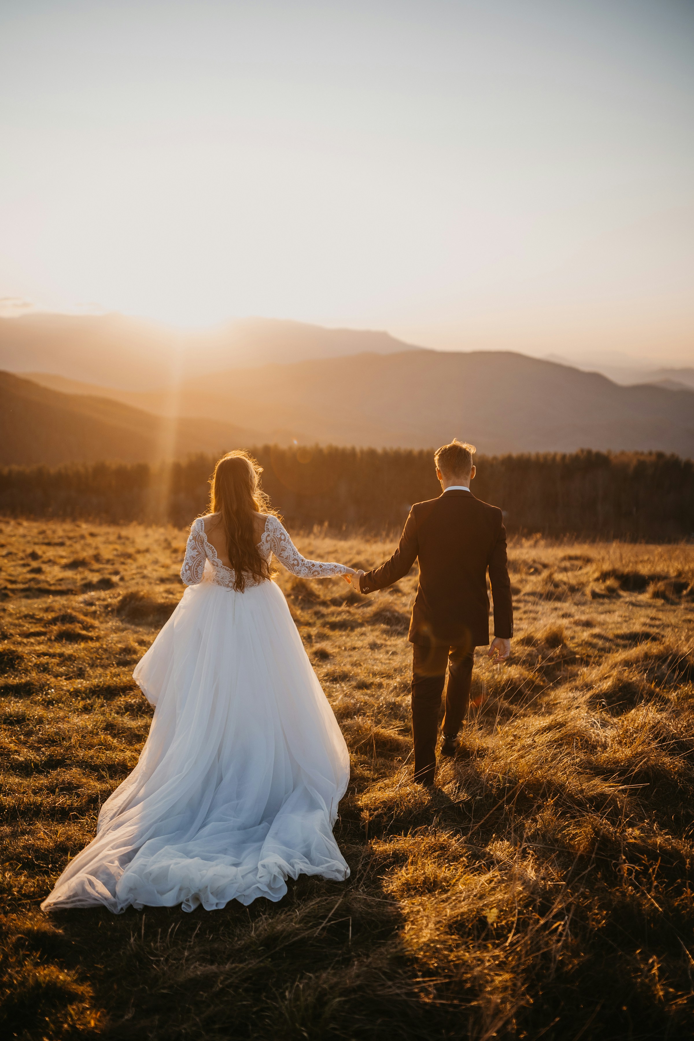 Unos novios atravesando un campo durante la hora dorada | Fuente: Unsplash