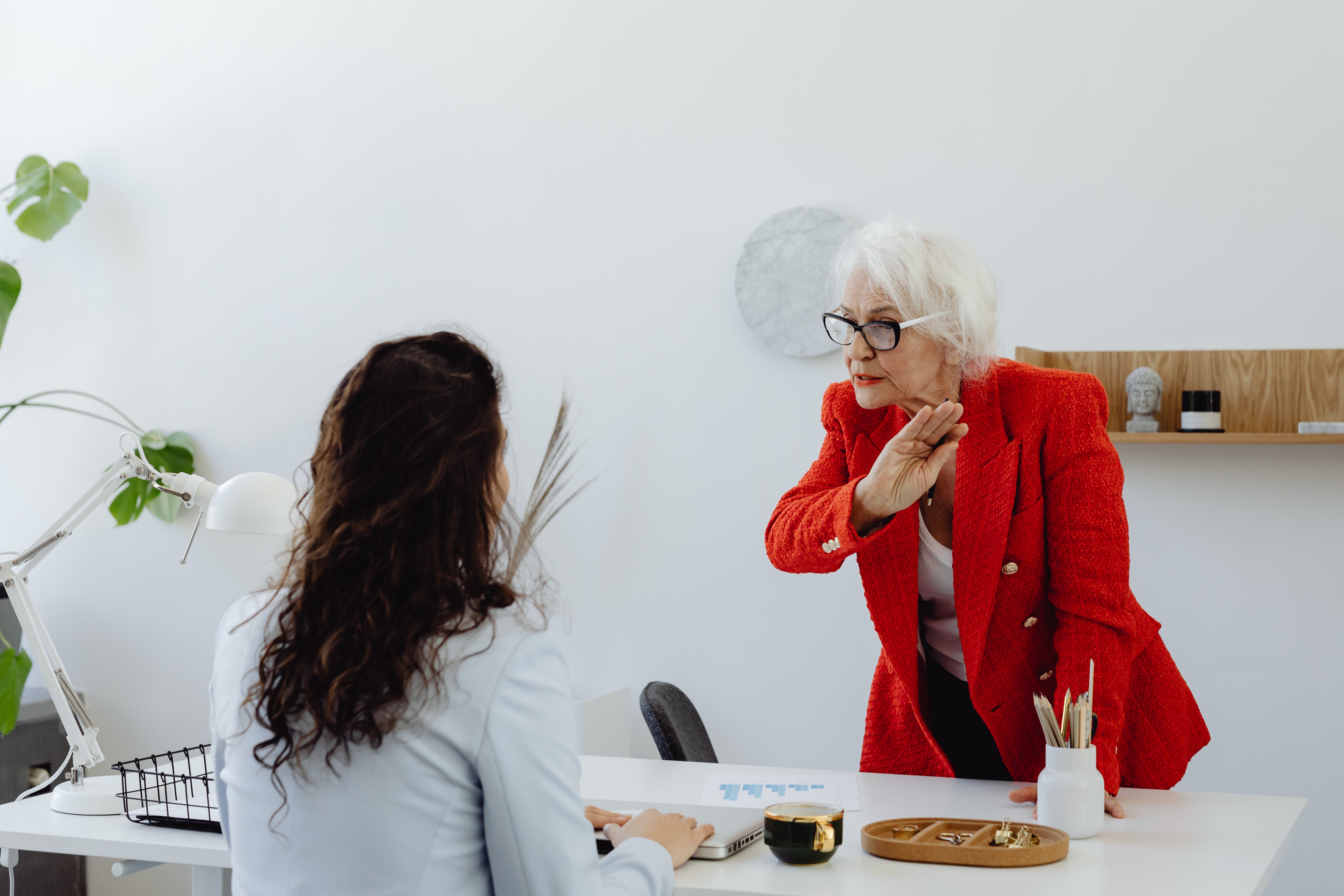 Una mujer mayor de pie discutiendo con otra más joven que está sentada | Foto: Pexels