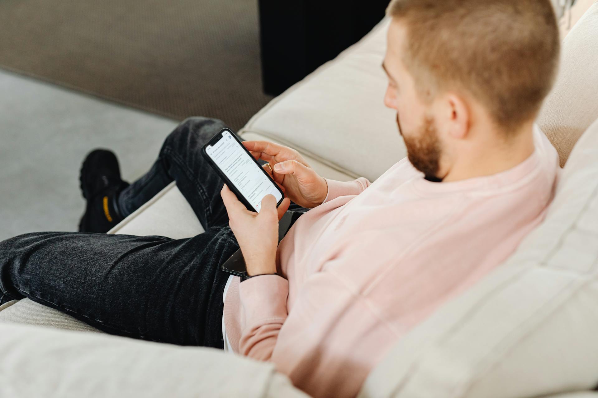Un hombre sentado en el sofá y utilizando su teléfono | Fuente: Pexels