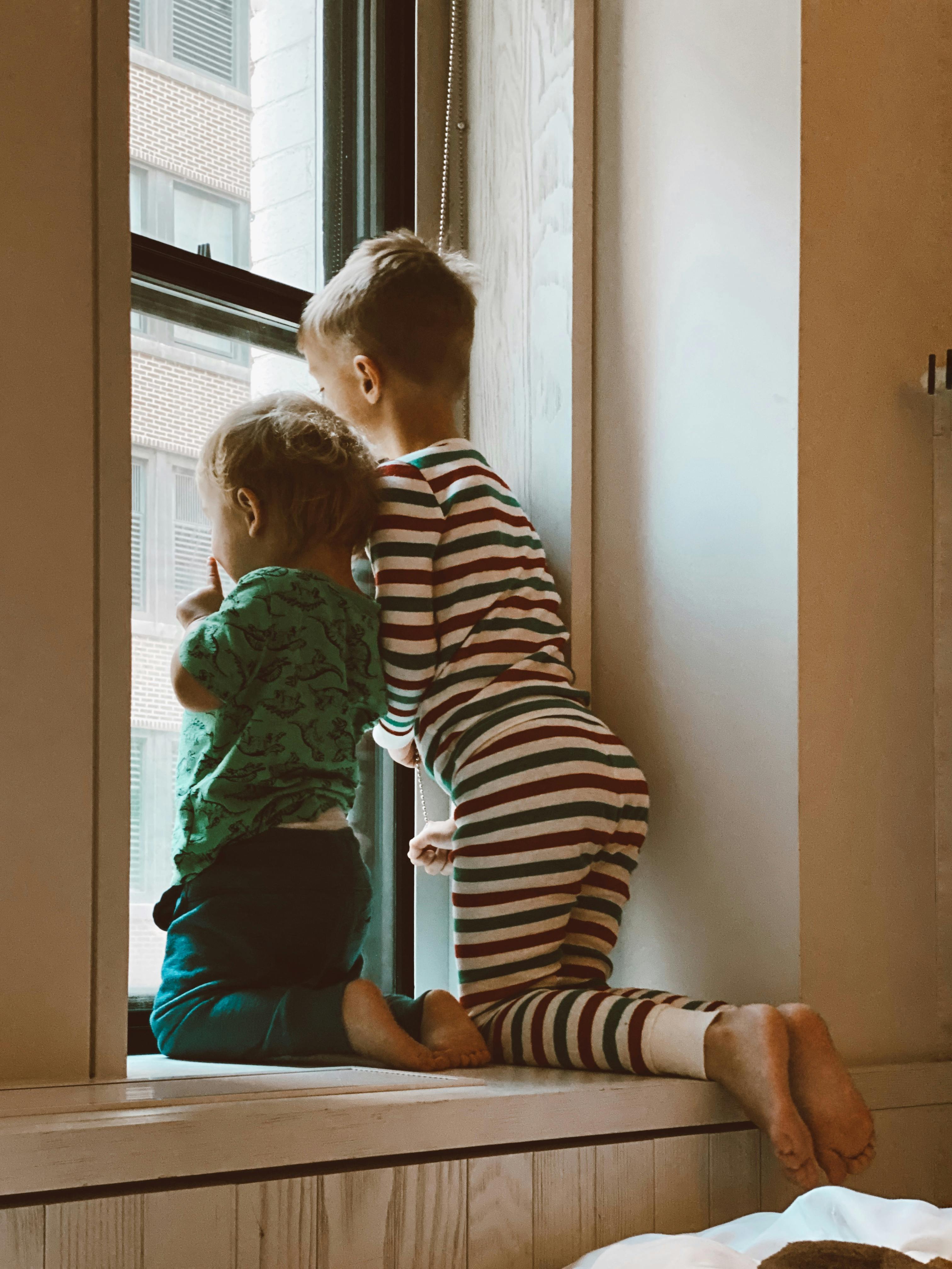 Dos niños mirando por la ventana | Fuente: Pexels