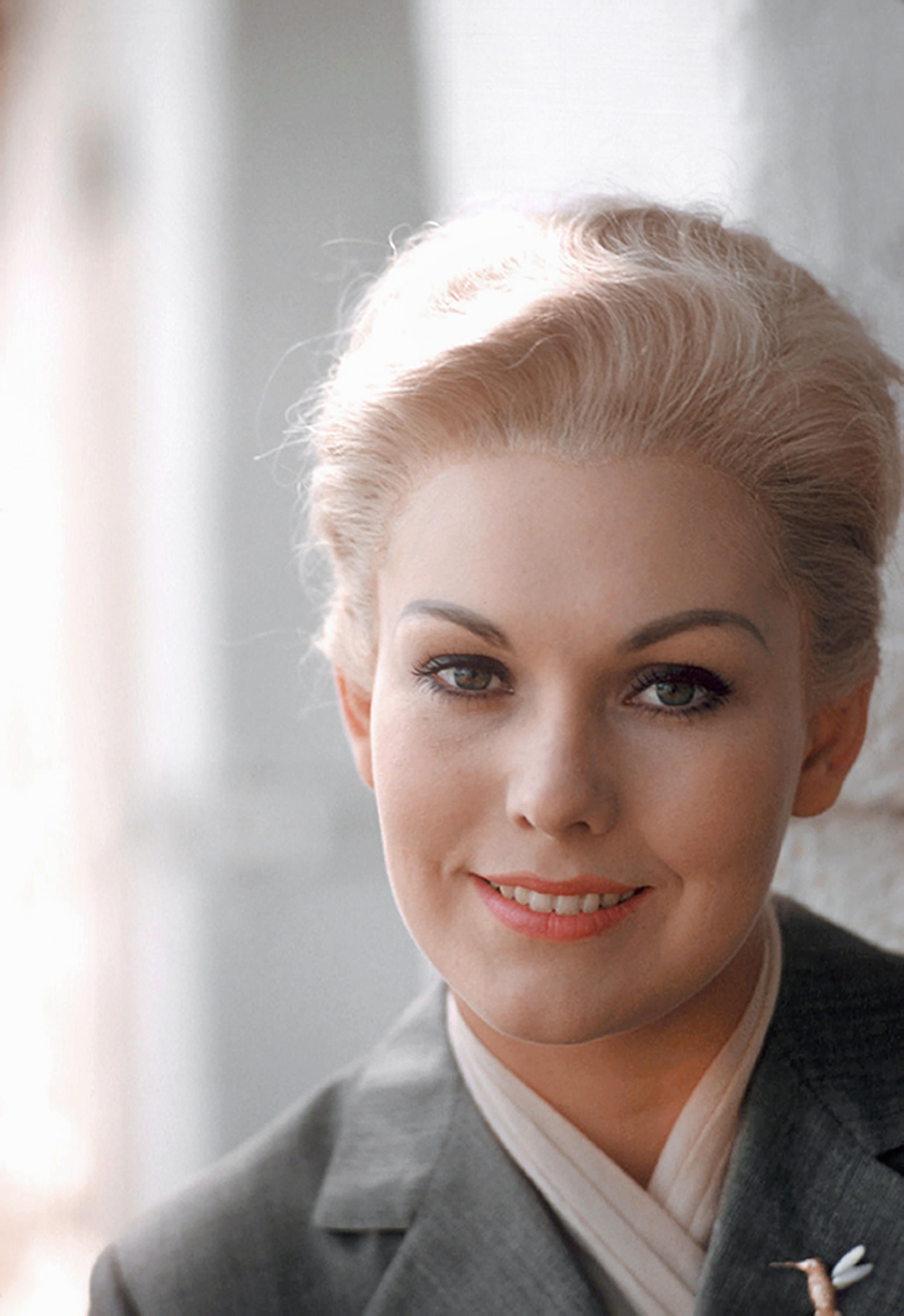 Kim Novak sonríe en un primer plano tomado durante una sesión en el plató de "Vertigo", con una chaqueta oscura sobre un top de color claro. | Fuente: Getty Images