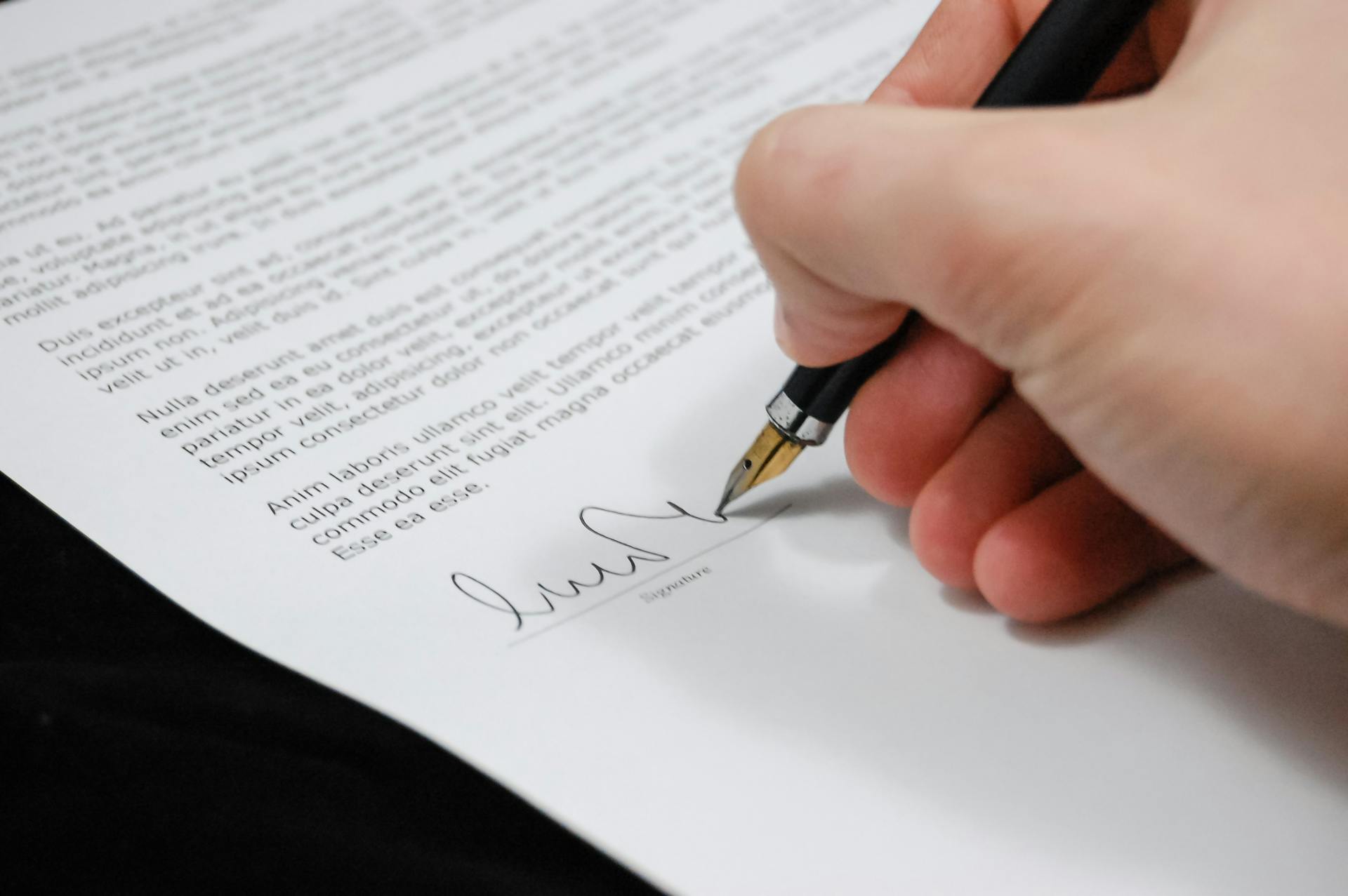 Una persona firmando un documento | Fuente: Pexels