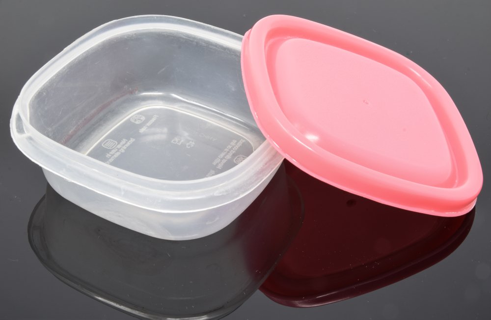 Pequeña caja de tupperware con tapa rosa. | Fuente: Shutterstock