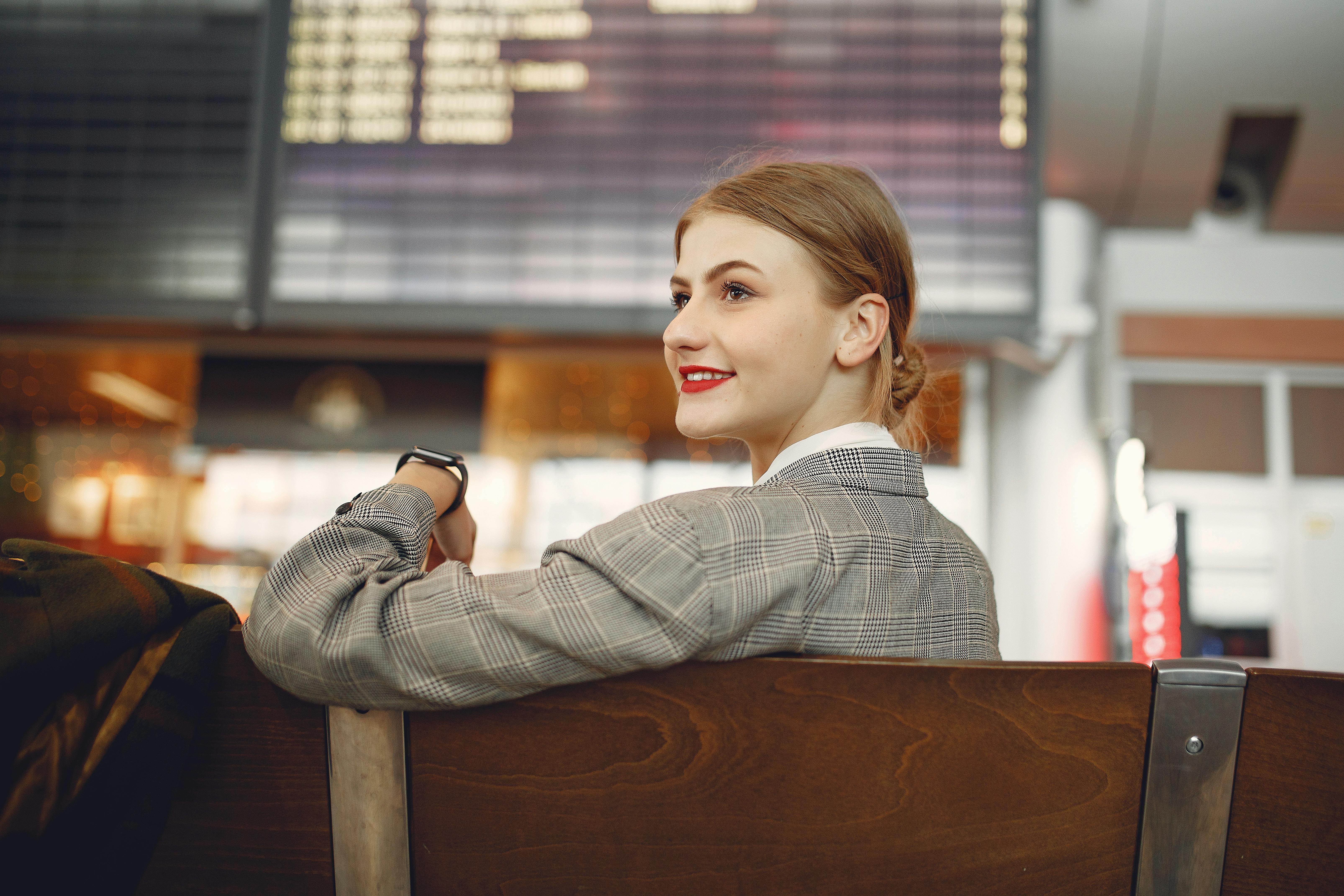 Una mujer feliz sentada en el aeropuerto | Foto: Pexels