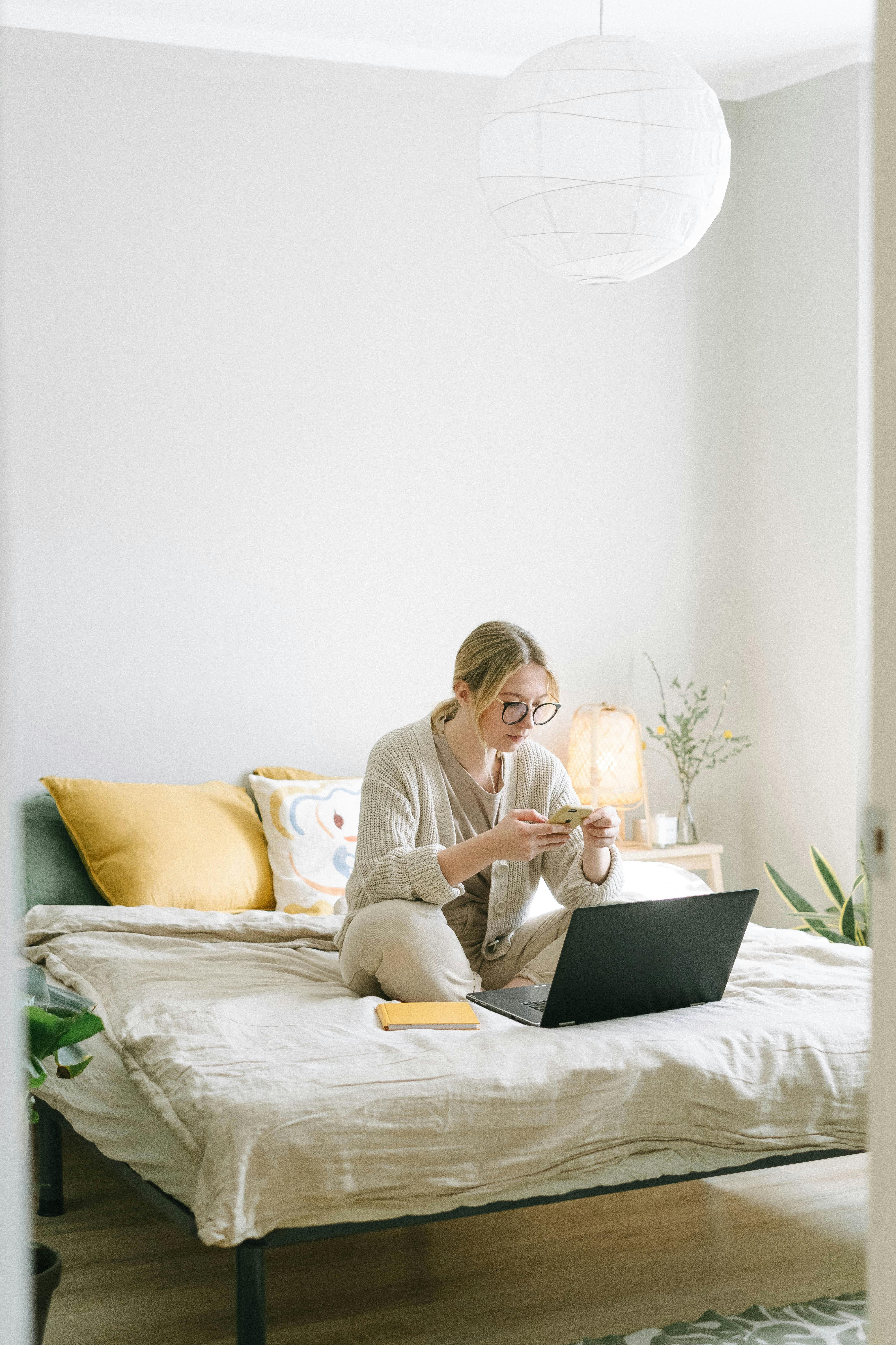 Una mujer escribiendo en su teléfono en su habitación | Fuente: Pexels