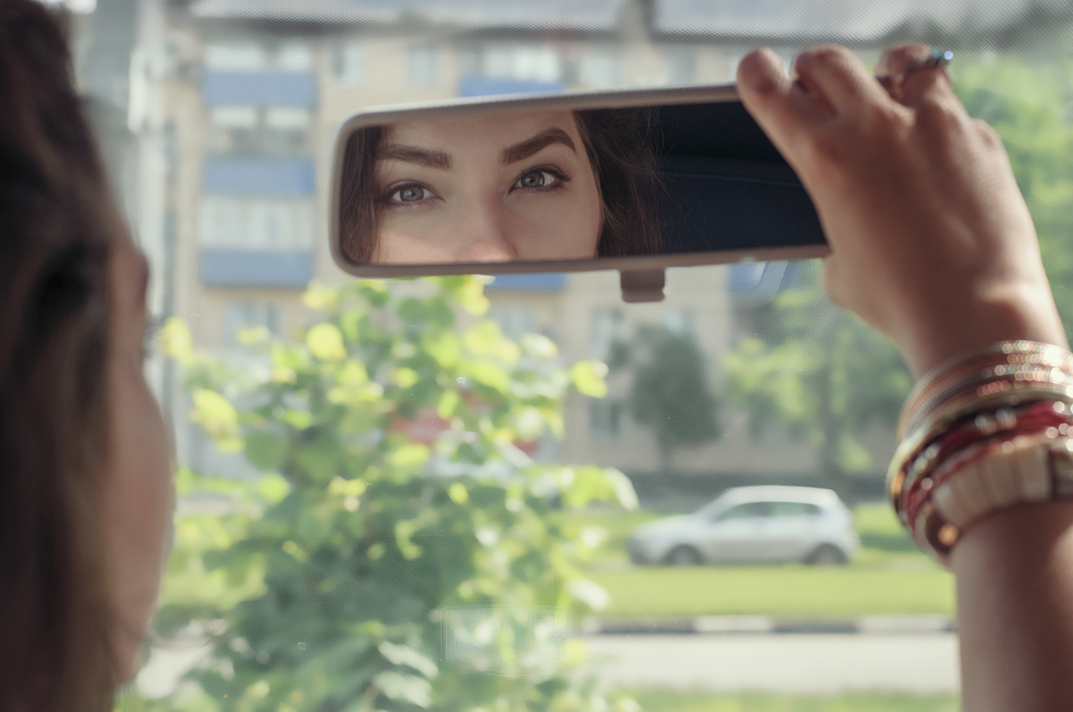 Mujer mirando su reflejo en el espejo retrovisor de un automóvil | Fuente: Shutterstock.com