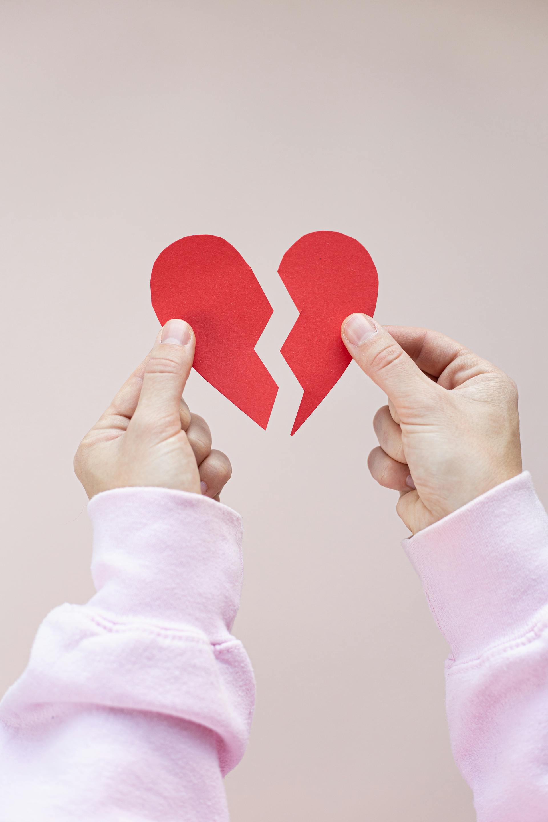 Una persona sostiene un corazón de papel rojo roto | Fuente: Pexels